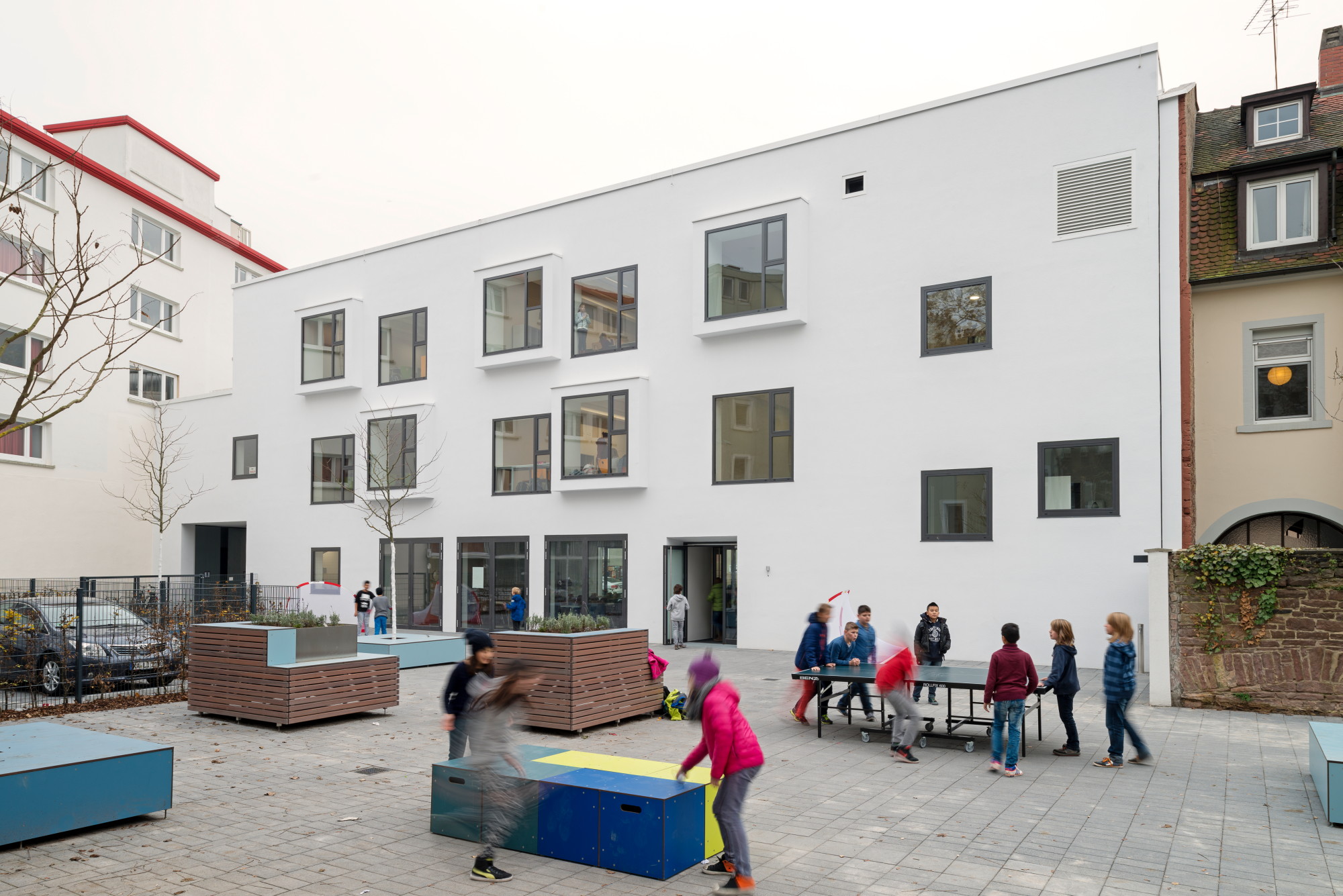 Die quadratischen Fenster auf der Hofseite sind leicht versetzt zueinander angeordnet; einige von ihnen treten ein Stück aus der Fassadenebene heraus