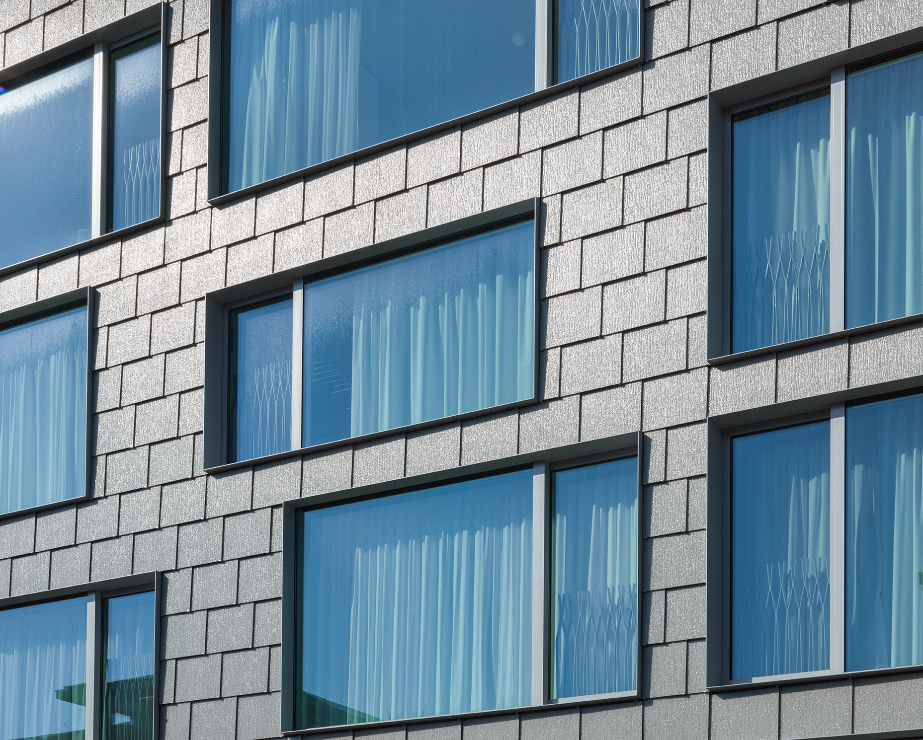Sämtliche Fassaden sind mit grauen, strukturierten Glasschindeln verkleidet