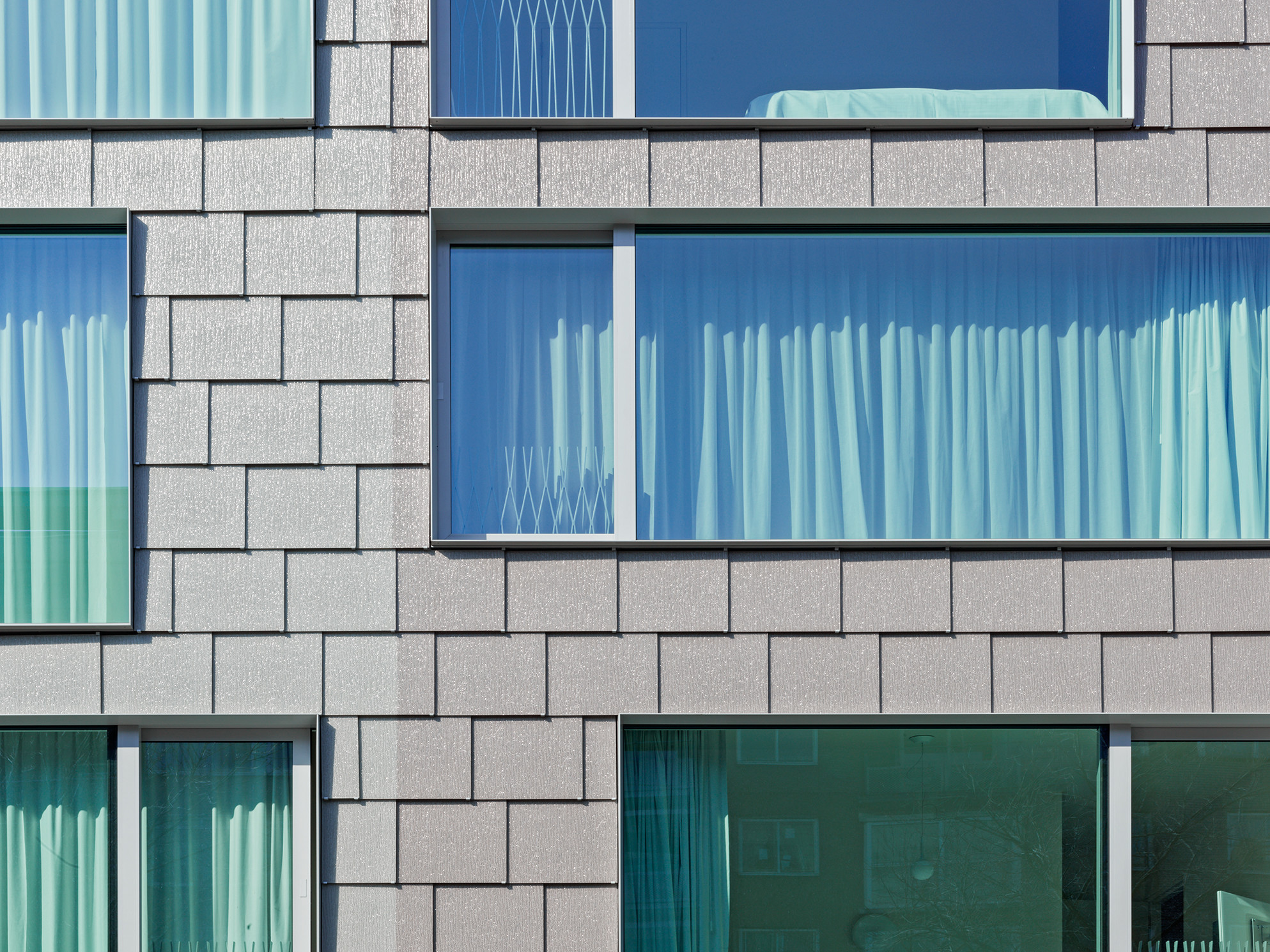 Die Straßenfassade ist in zwei unterschiedlichen Grauschattierungen gehalten, wodurch eine optische Zweiteilung entsteht