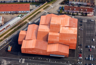 Die Mehrzweckhalle entstand auf dem Gelände eines ehemaligen Busdepots in einem Mischgebiet von Saint-Louis 