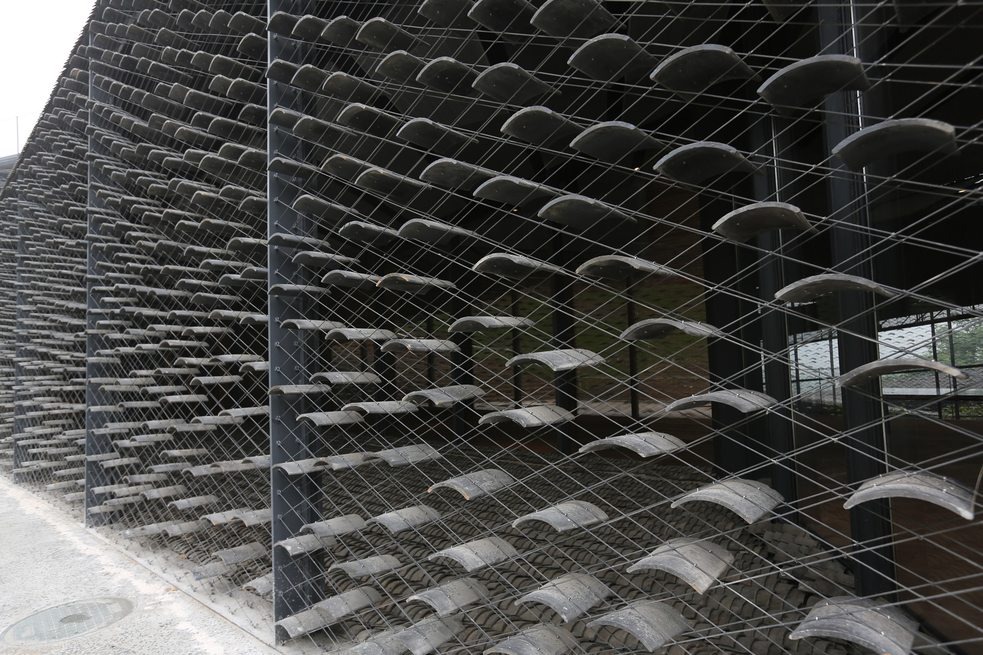 Rund sieben Millionen Tonziegel wurden für die Dächer und Fassaden verwendet: Vor den Stahl-Glas-Fassaden schweben sie in einer Matrix aus feinem Stahldraht