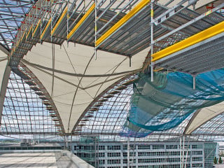 Bei laufendem Betrieb erfolgt der Austausch der Dachmembran am Flughafen München - Schutznetze und die Schutzdachkonstruktion garantieren die Sicherheit der Passanten