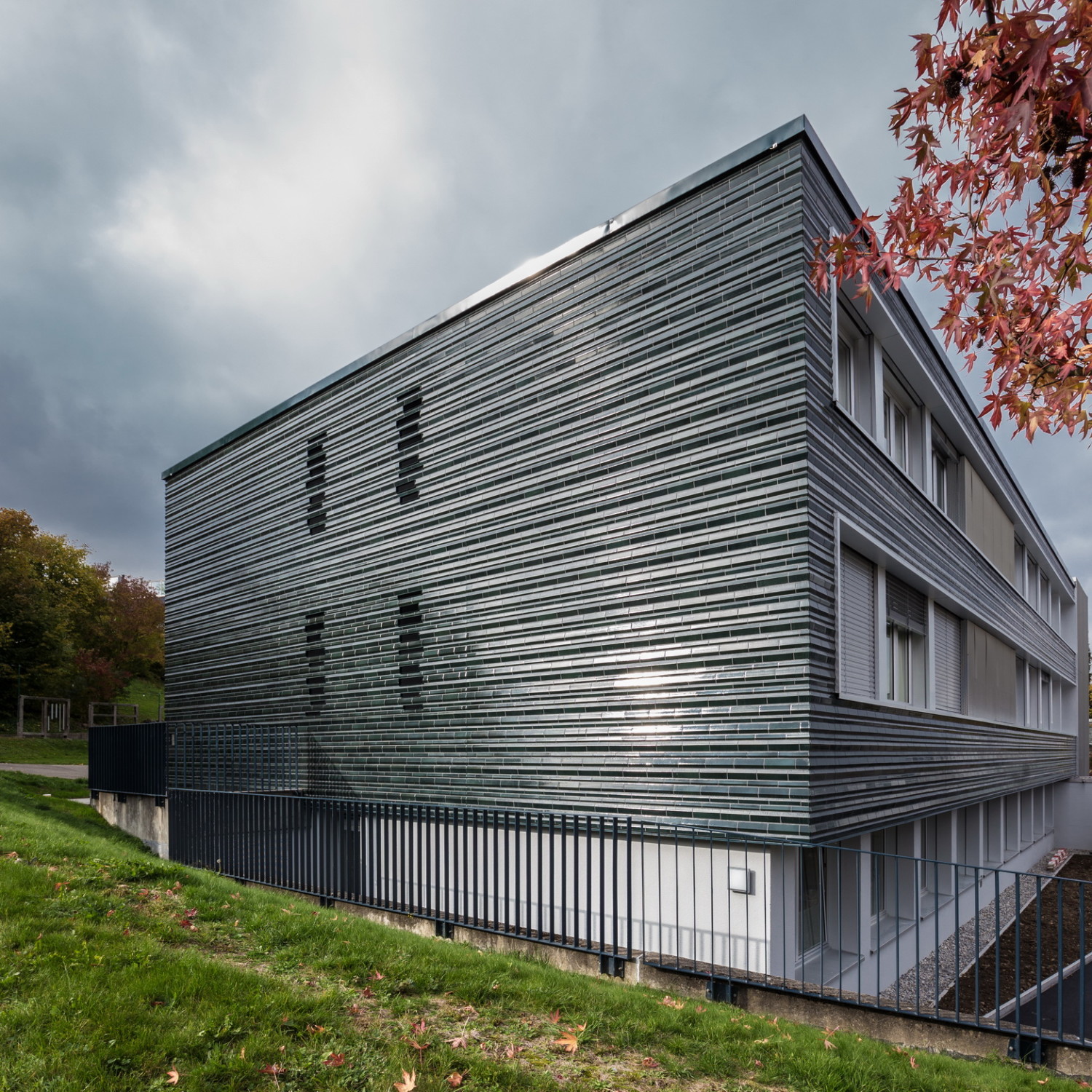 Die Fassade erhielt ein neues Kleid: die Architekten wählten dafür glasierte Profilfliesen in einem changierenden, dunklen Grünton