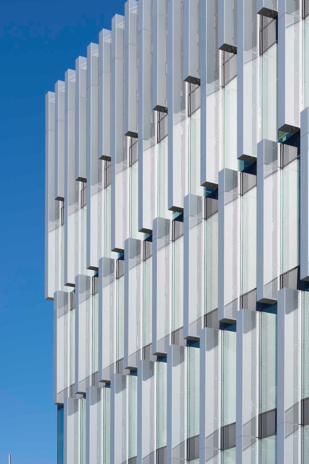 Eine Perforation in den vertikalen Lamellen an der Fassade sorgt für eine natürliche Belüftung des Gebäudes 