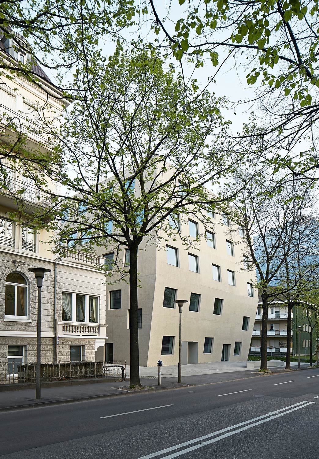Der warme Sandton der weitgehend fugenfreien Sichtbetonfassade ist abgestimmt auf die blasse Farbigkeit des denkmalgeschützten Bestands