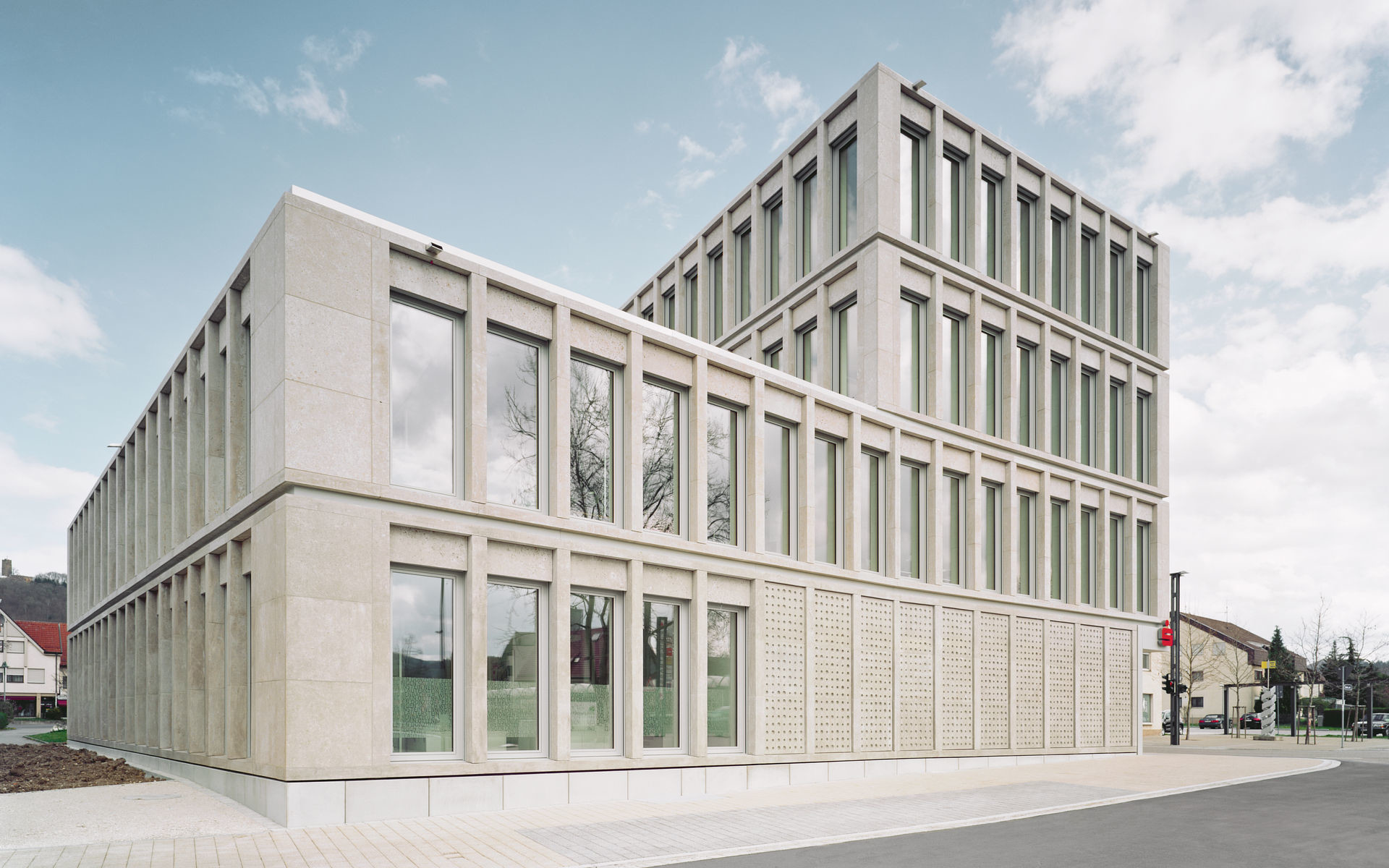 Hochrechteckige Fensteröffnungen rhythmisieren die Fassade aus Muschelkalk
