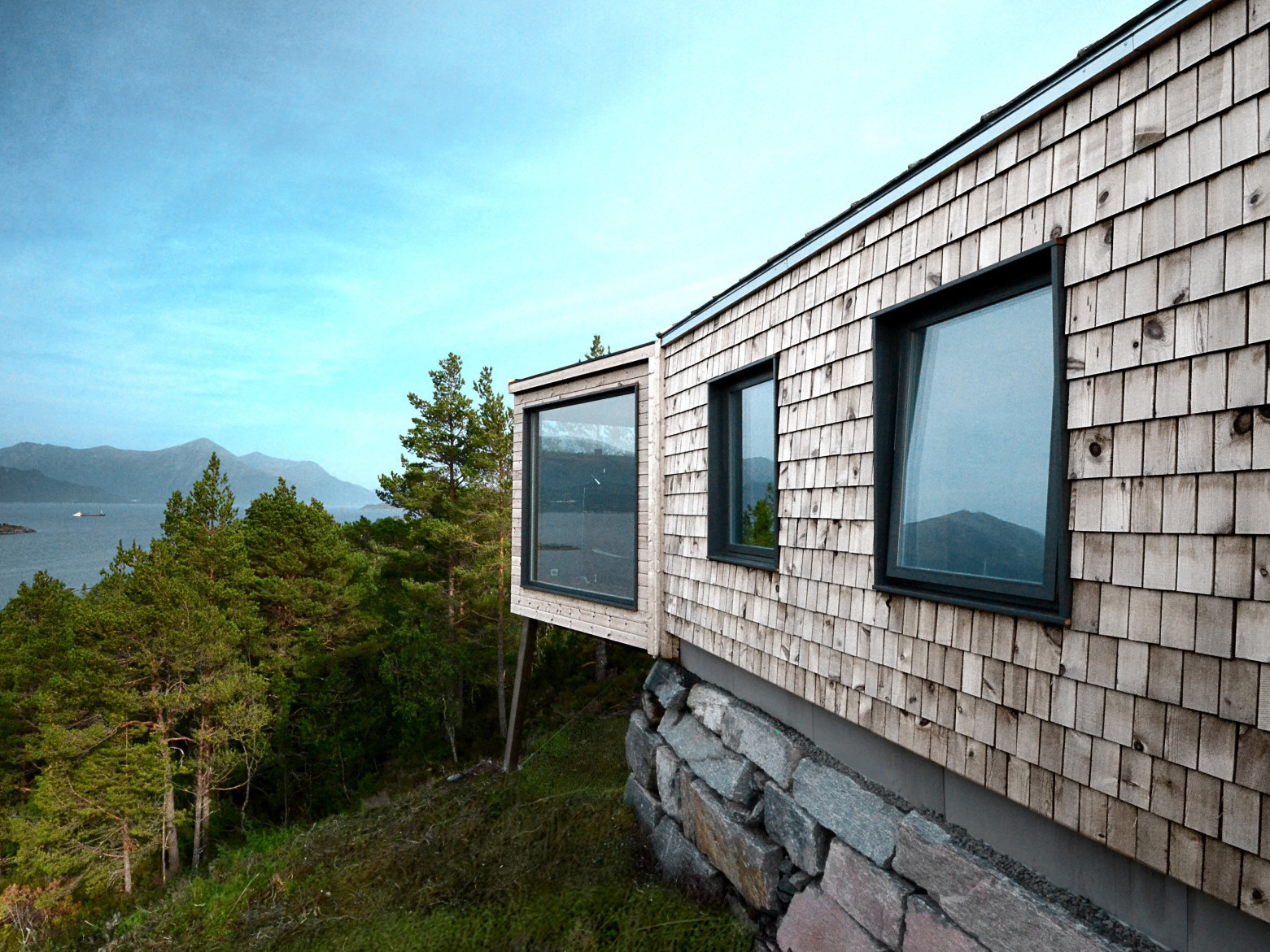Holz als Schindeln und horizontale Bretter sowie Naturstein sind die prägenden Materialien