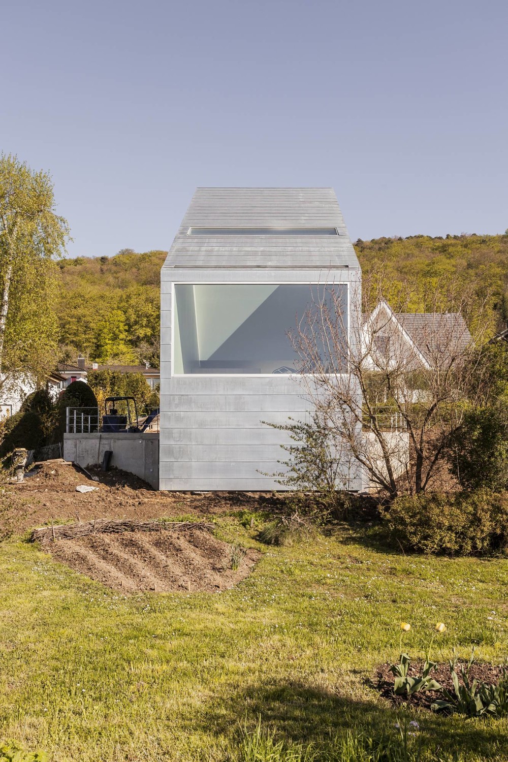 Die Schmalseiten und das Dach erhielten eine Haut aus Kupfertitanzink; der Wohnraum öffnet sich mit einem großen Fenster zur Landschaft