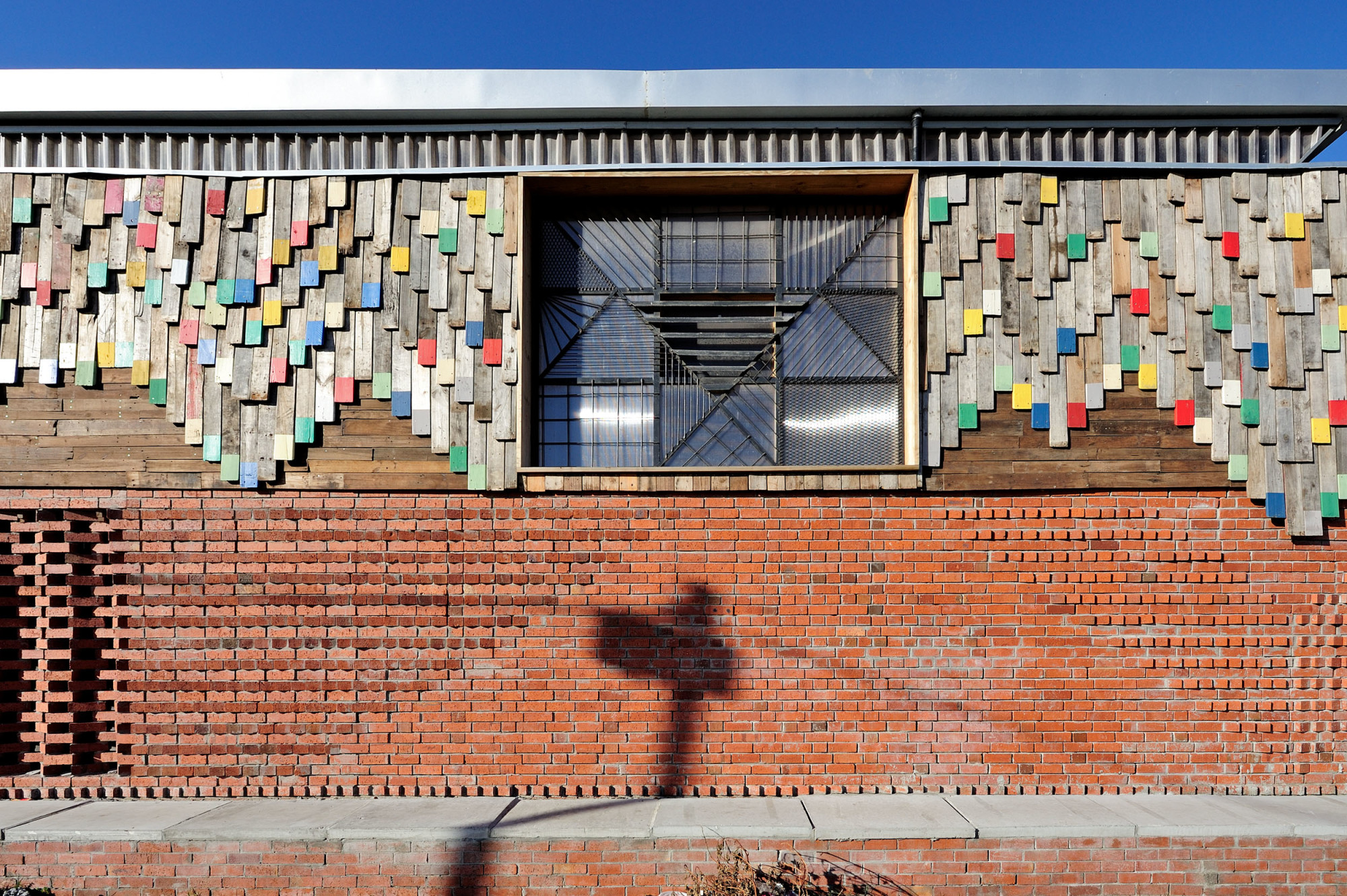 Die Farbgestaltung der Holzfassade ist inspiriert durch die Ornamentik traditioneller Textilien