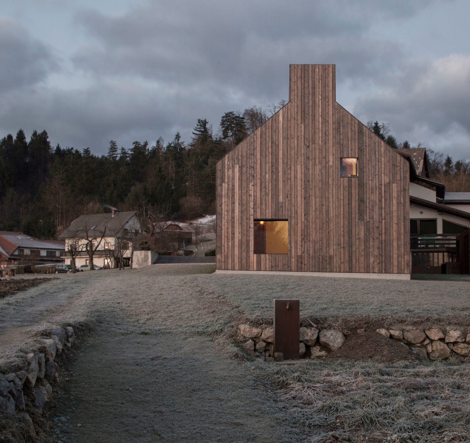 Die Kontur des Kamins durchbricht die archaische Form des Hauses (Ostansicht)