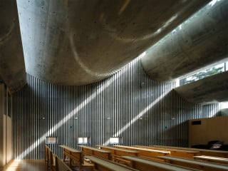 Architekt Takeshi Hosaka entwarf ein Gebetshaus mit monolithischer Wirkung, dessen wellenartig ausgeformtes Dach in unterschiedliche Höhen zu wogen scheint (Südostansicht)