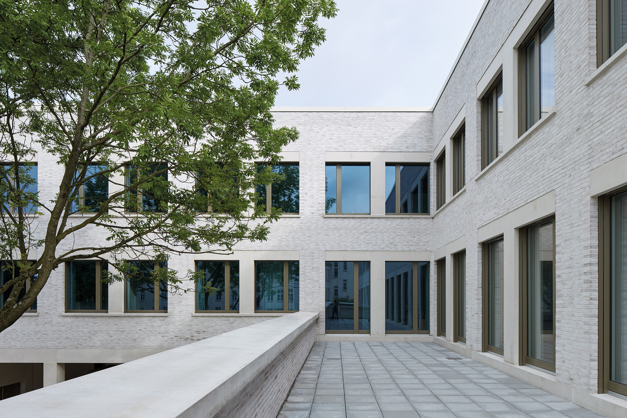Die hellen Fensterfaschen aus Sichtbeton gliedern die geschlämmten Klinkerfassaden und stellen Bezüge zu dem im Altbau verwendeten Sandstein her