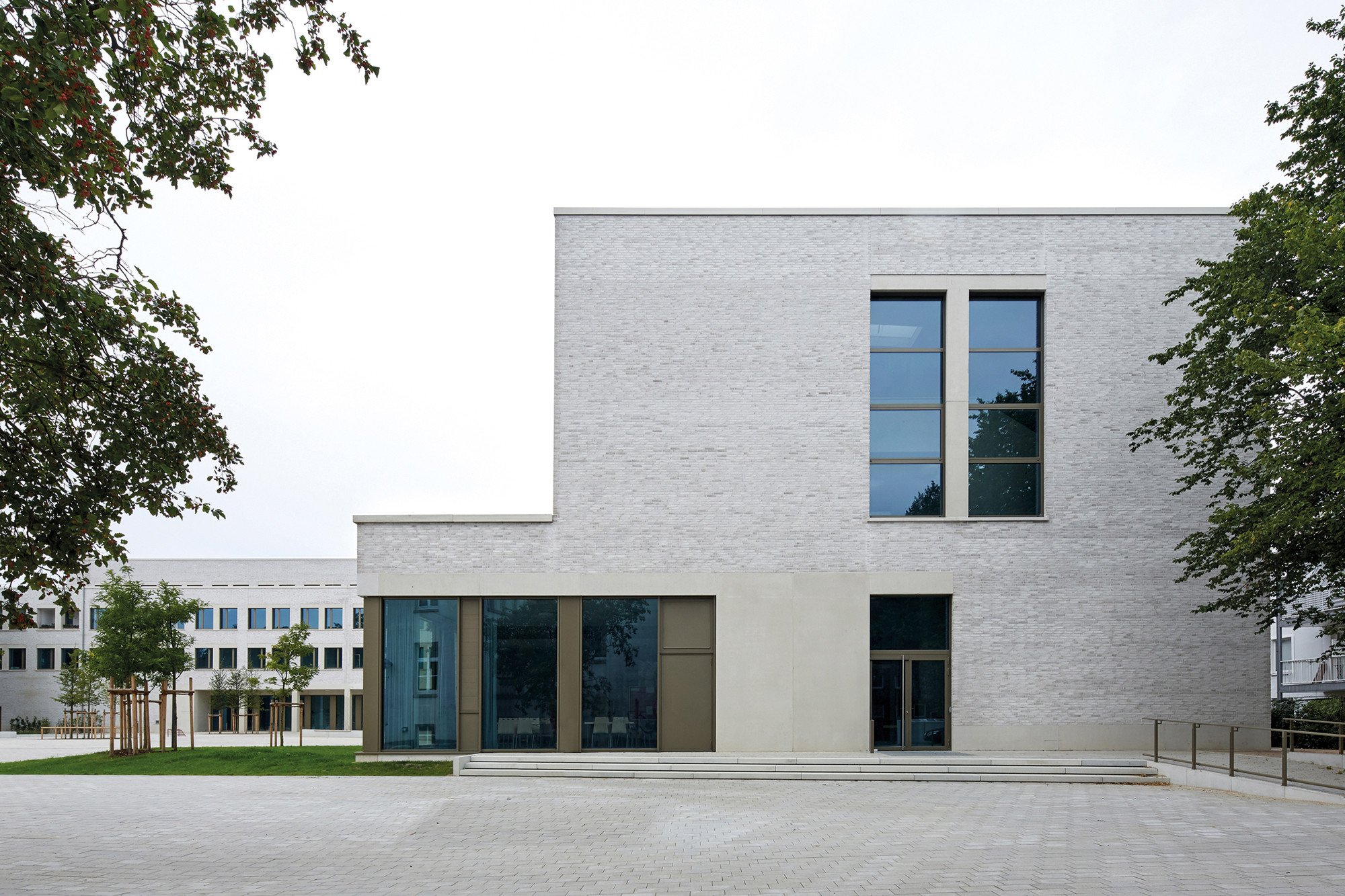 Der L-förmige, dreigeschossige Neubau mit doppelgeschossiger Sporthalle entstand losgelöst vom Altbau und schließt den gemeinsamen Pausenhof im Norden und Osten ab