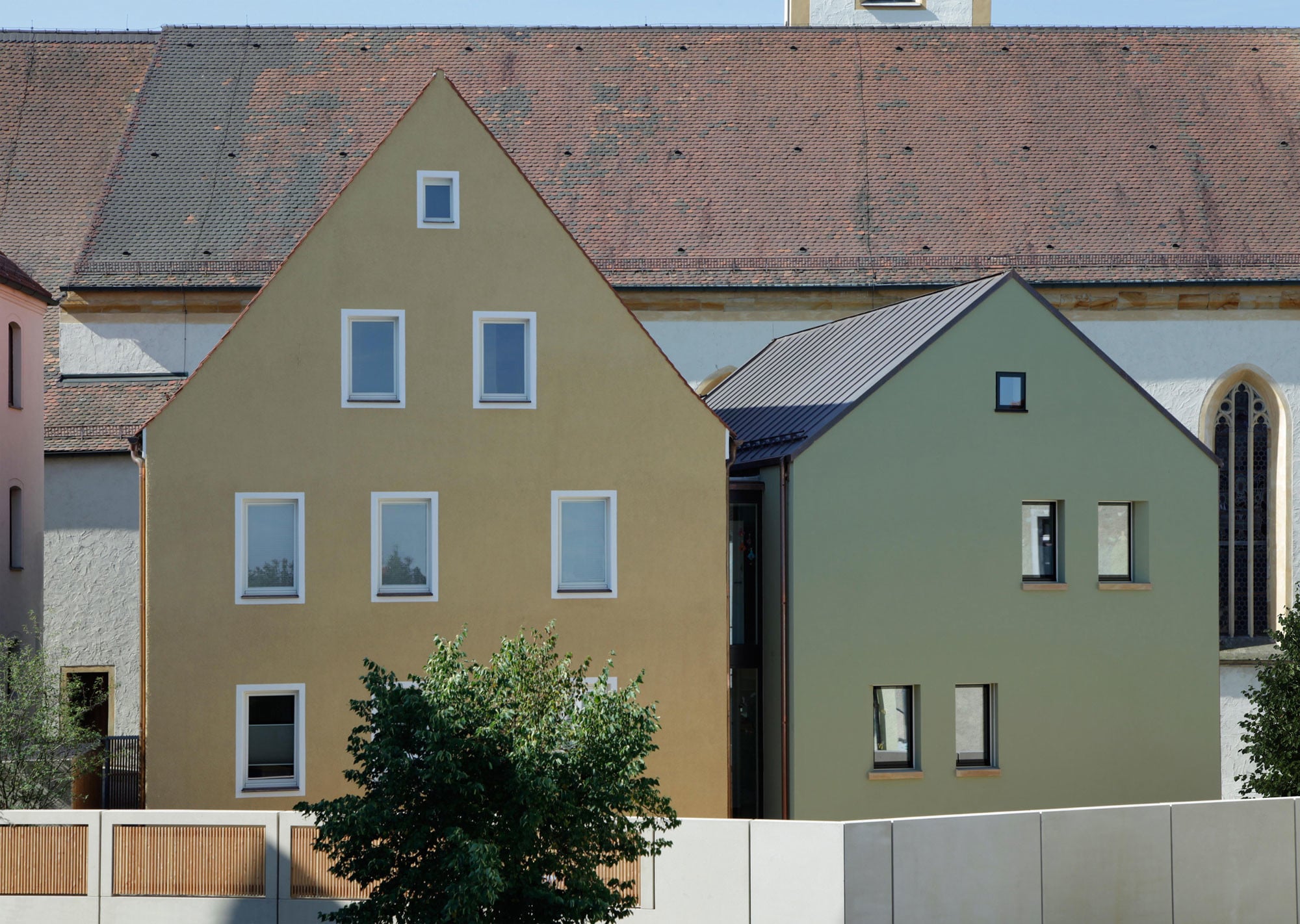 Die Kinderkrippe Stadtzwerge in Schwandorf von Architekt Karlheinz Beer ist in einem Ensemble untergebracht. Für dessen Erhalt wurde das Mesnerhaus (links) saniert und modernisiert, das kleinere Otthaus in Kubatur und Bauweise des Bestandsgebäudes als massives Ziegelbauwerk wiedererrichtet
