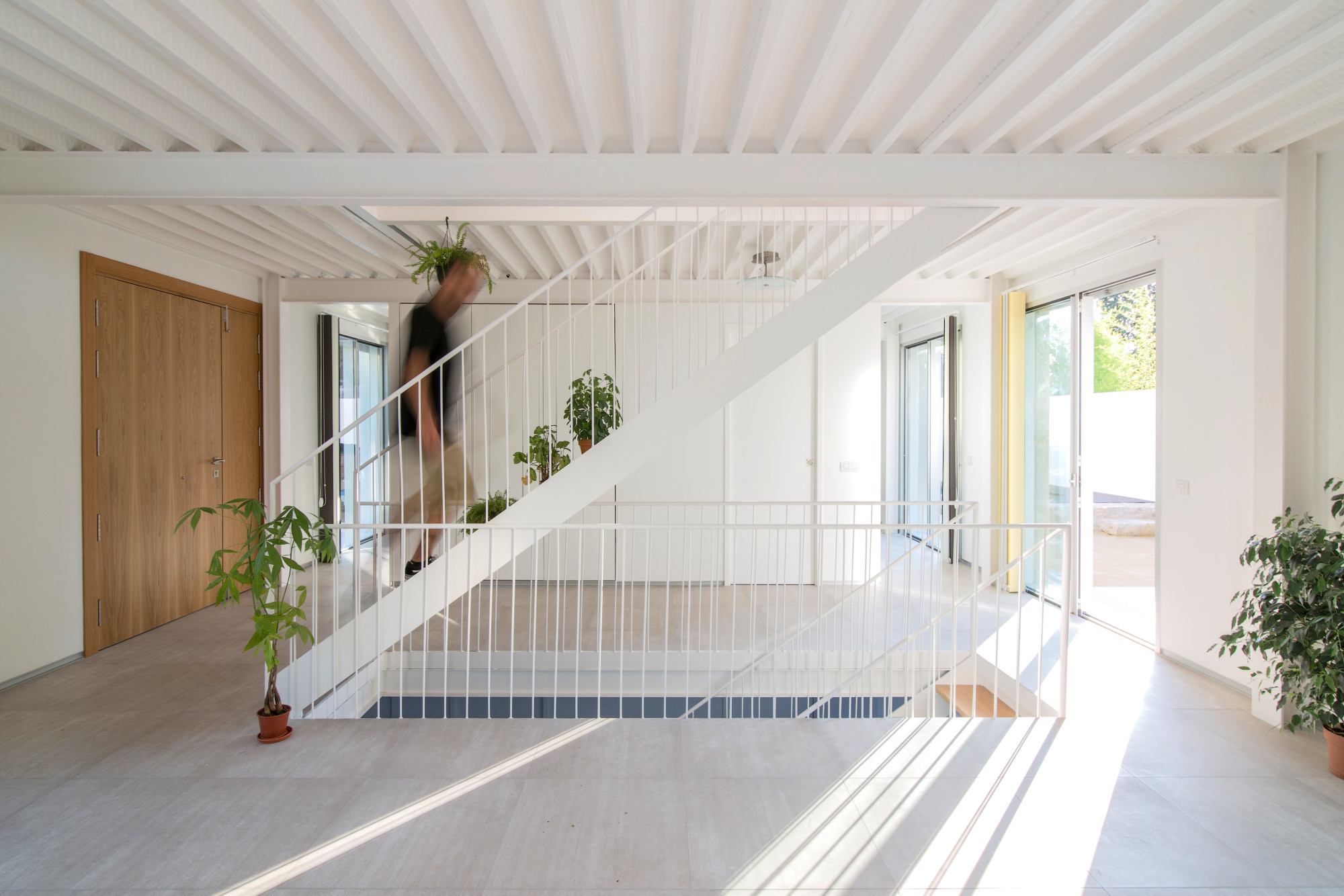 Die im Haus nahezu mittig angeordnete offene Treppe mit weißem Stahlgeländer verbindet die Ebenem vom Keller bis zum zweiten Obergeschoss