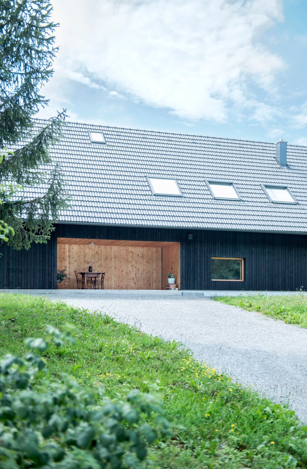 Die Fassade des Holzbaus nach Plänen von Bogenfeld Architektur ist mit dunkel lasierten Fichtenlatten bekleidet, der Eingang liegt zurückversetzt in einer Nische (Nordansicht)