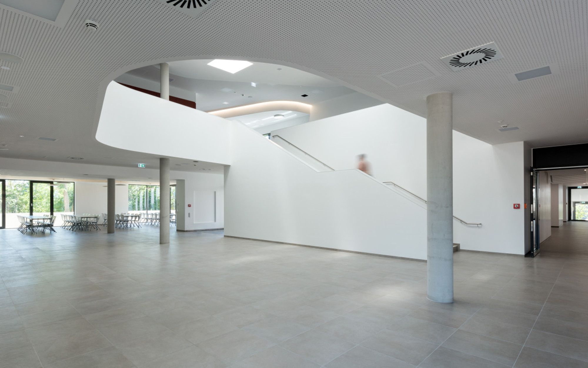 An der Schnittstelle der beiden Gebäudetrakte befindet sich der Zugang, der ins Foyer, das auch als Aula dient, leitet 