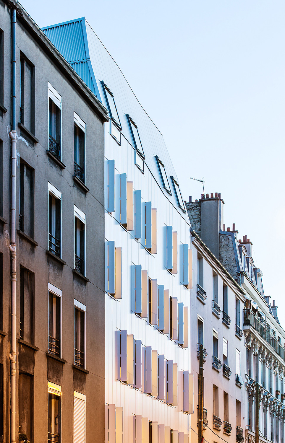 Zur Straßenseite nach Westen besteht die Fassade aus weiß lackiertem Stahlblech; aus dem gleichen Material sind die Faltläden vor den bodentiefen Fenstern