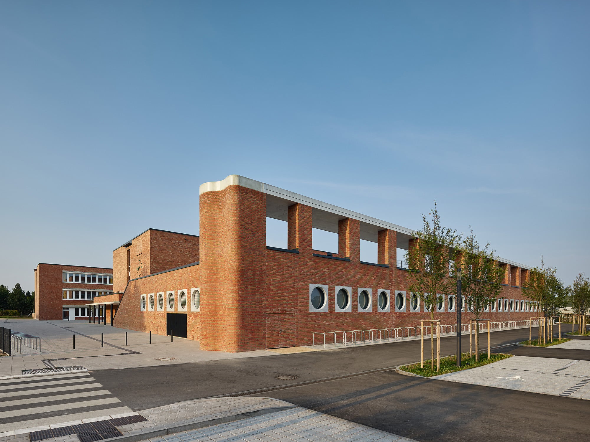 Zur verkehrsreichen Straße im Norden ist dem Schulltrakt eine Sporthalle mit begehbarem Dach vorgelagert