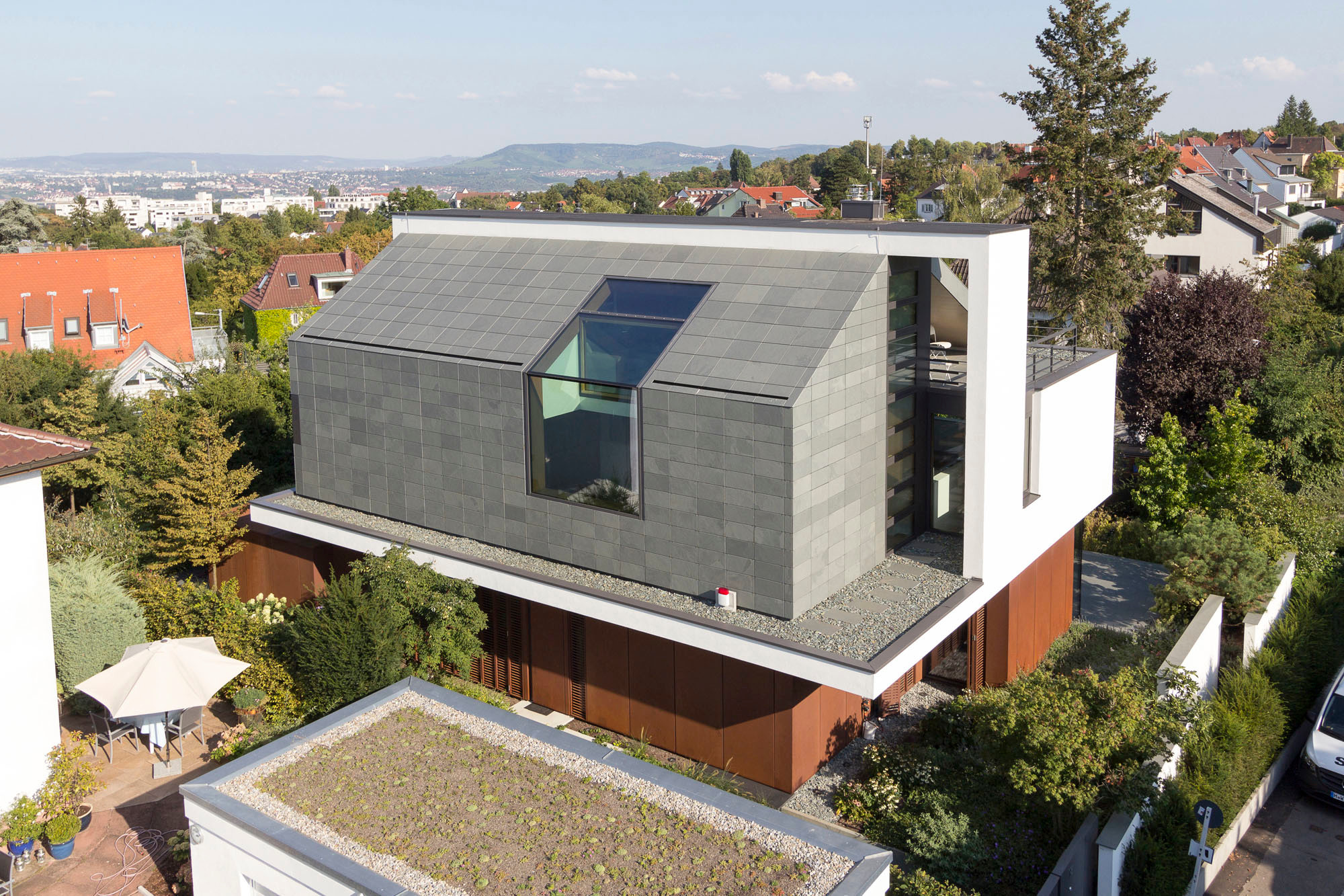 Eine riesige Verglasung wird aus der Fassade des Obergeschosses in die Dachschräge fortgeführt und belichtet einen verbindenden Luftraum oberhalb des Eingangs