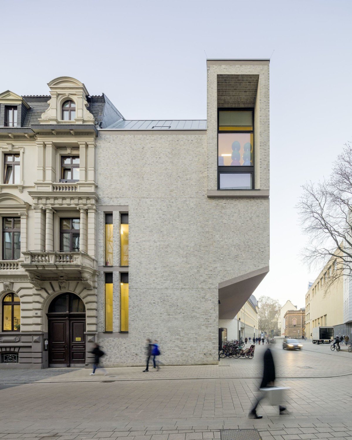 Ein Unterschnitt in der Fassade des mit hellen Ziegeln verblendeten Neubaus kennzeichnet den Eingang