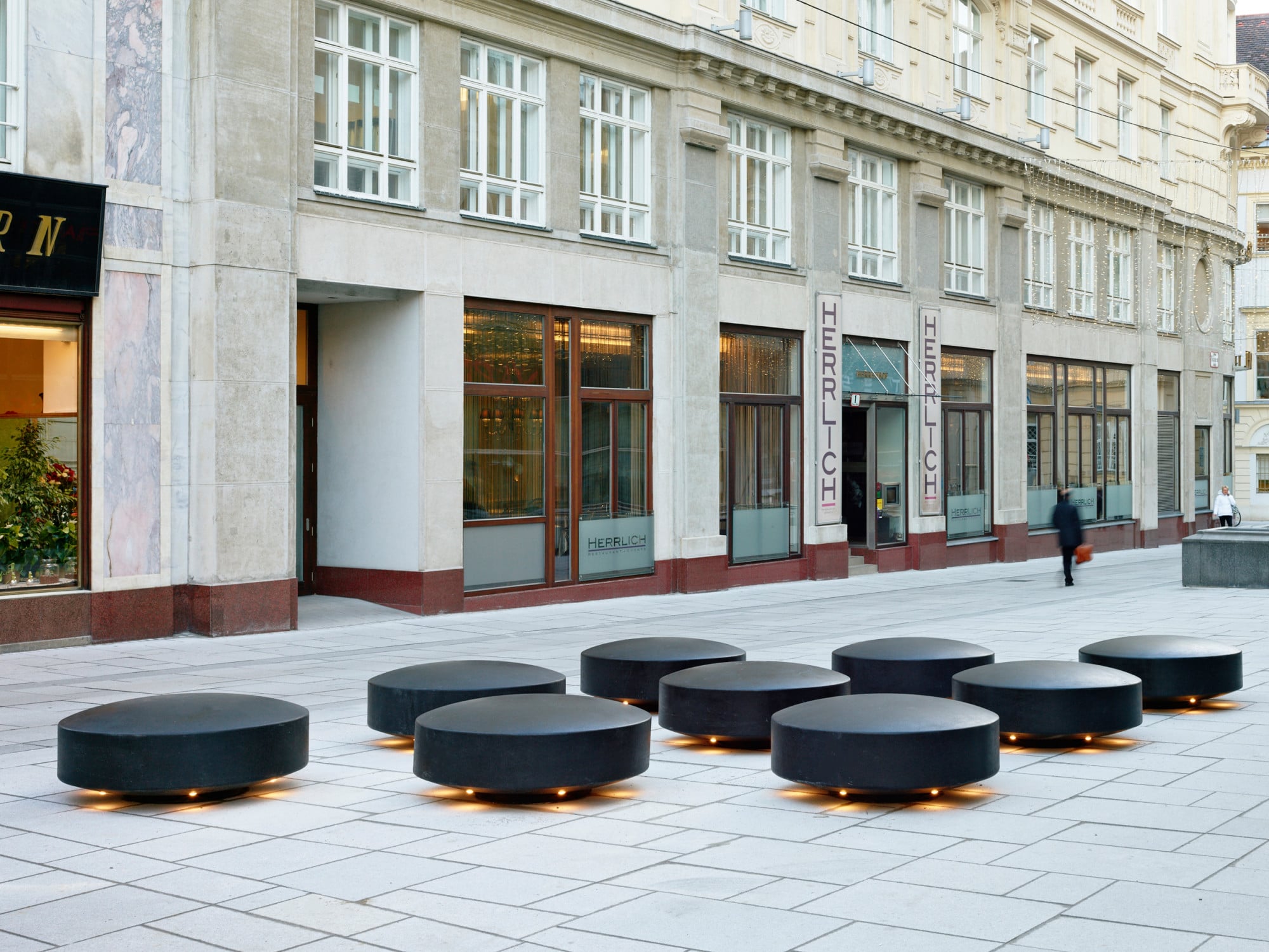 Neun matt-schwarze Steine laden Passanten vor dem Hochhaus Herrengasse in Wien zum Verweilen ein