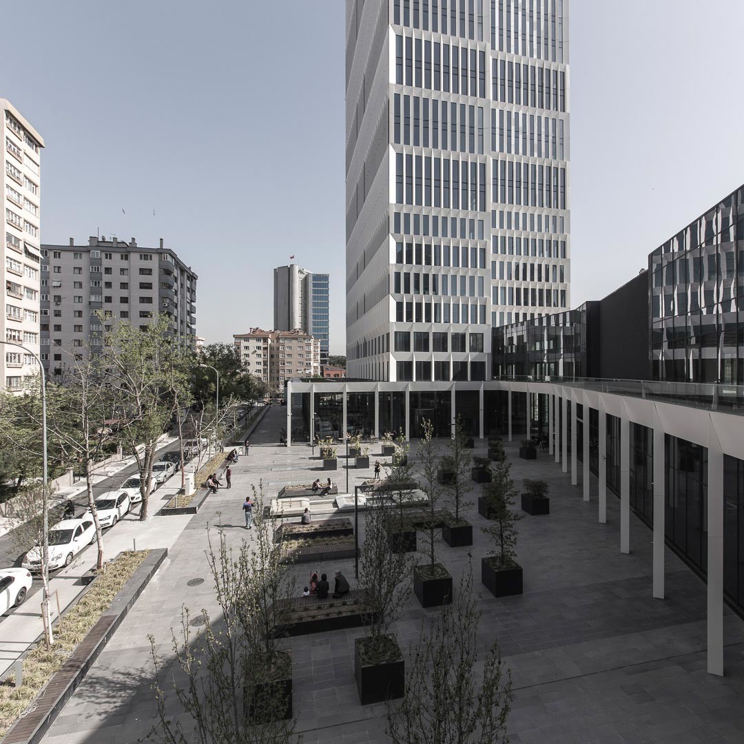 Der dreigeschossige Sockel fasst auf der von der Schnellstraße abgewandten Gebäudeseite einen öffentlichen Platz