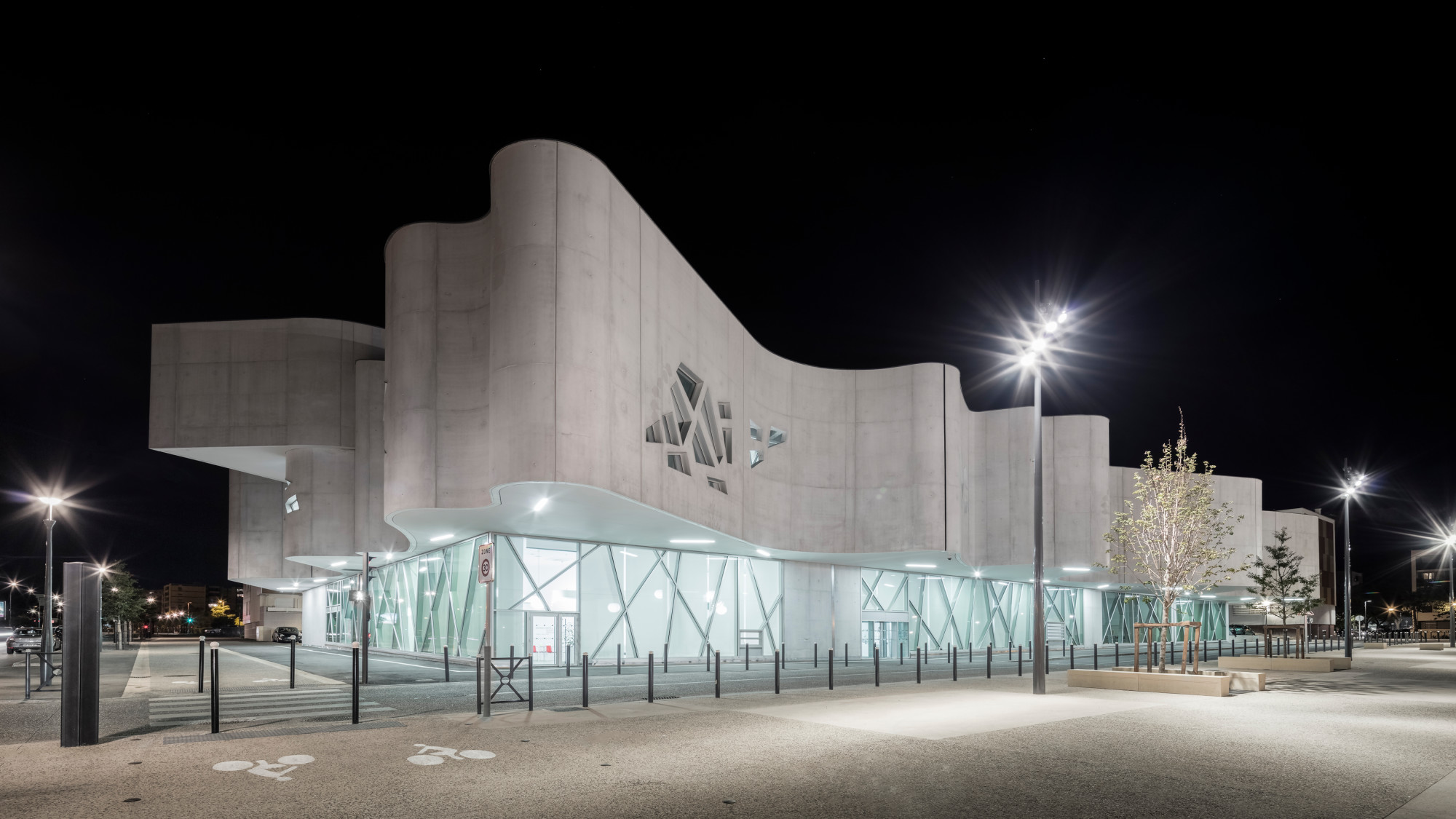 Während das erste Obergeschoss über das Erdgeschoss auskragt, weichen die beiden darüber liegenden Stockwerke zurück, sodass sie vom Straßenniveau aus kaum sichtbar sind