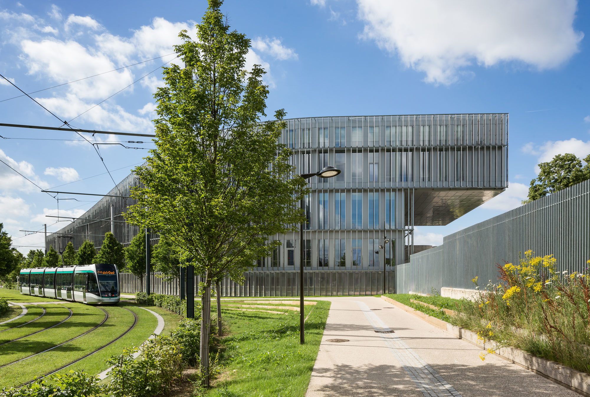 Die Gebäudehöhe steigt um mehr als ein Vollgeschoss an, bis sich das flache, um etwa zehn Meter auskragende Obergeschoss dem westlichen Campus zuwendet
