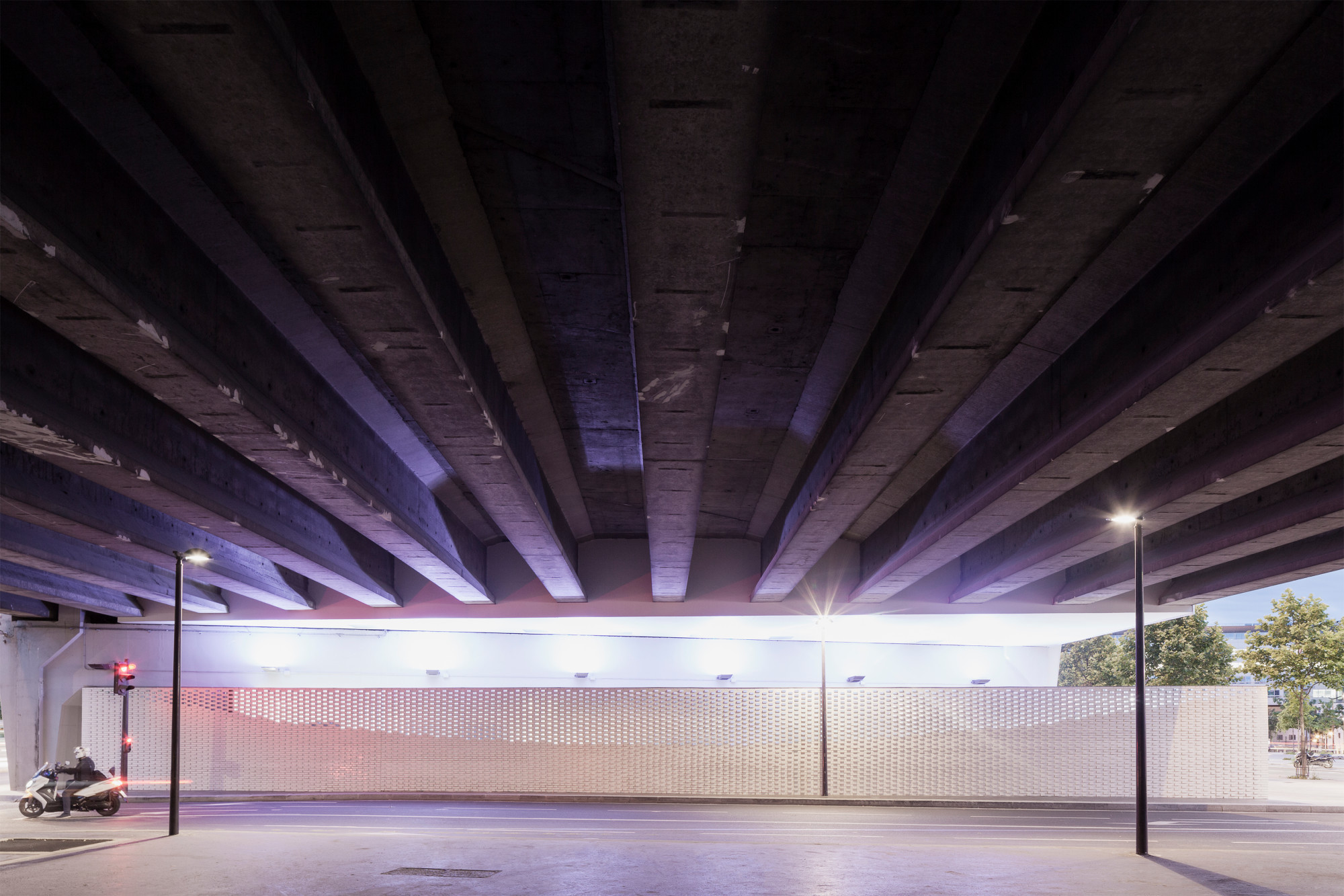 Über dem Recyclingzentrum verläuft der Boulevard Péripherique in Nord-Südrichtung (Ansicht Nord); Mastleuchten erhellen die Unterführung
