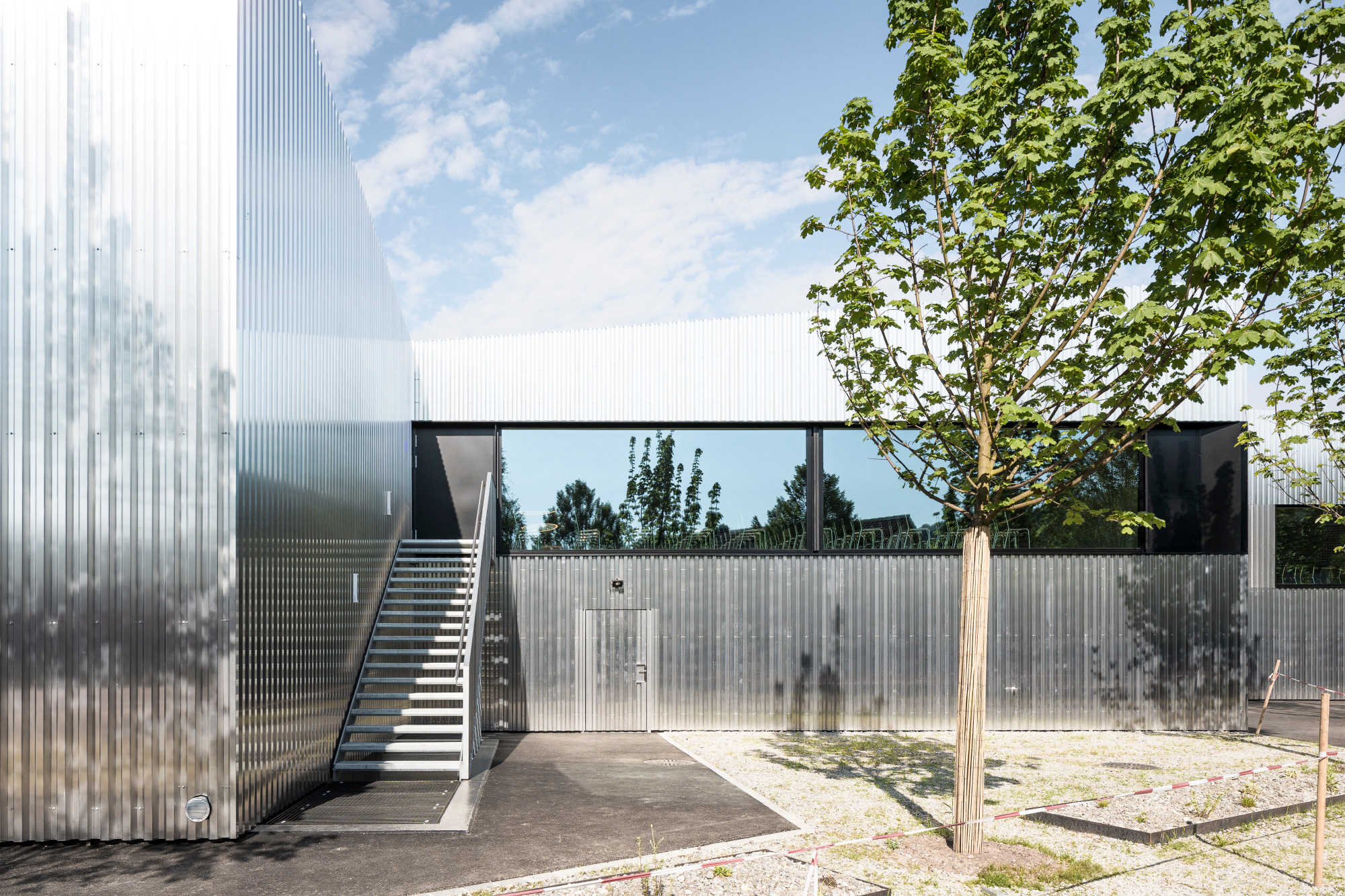 Große, liegende Fenster mit matt schwarzen Metallrahmen bilden einen Kontrast zum hellen Aluminium  