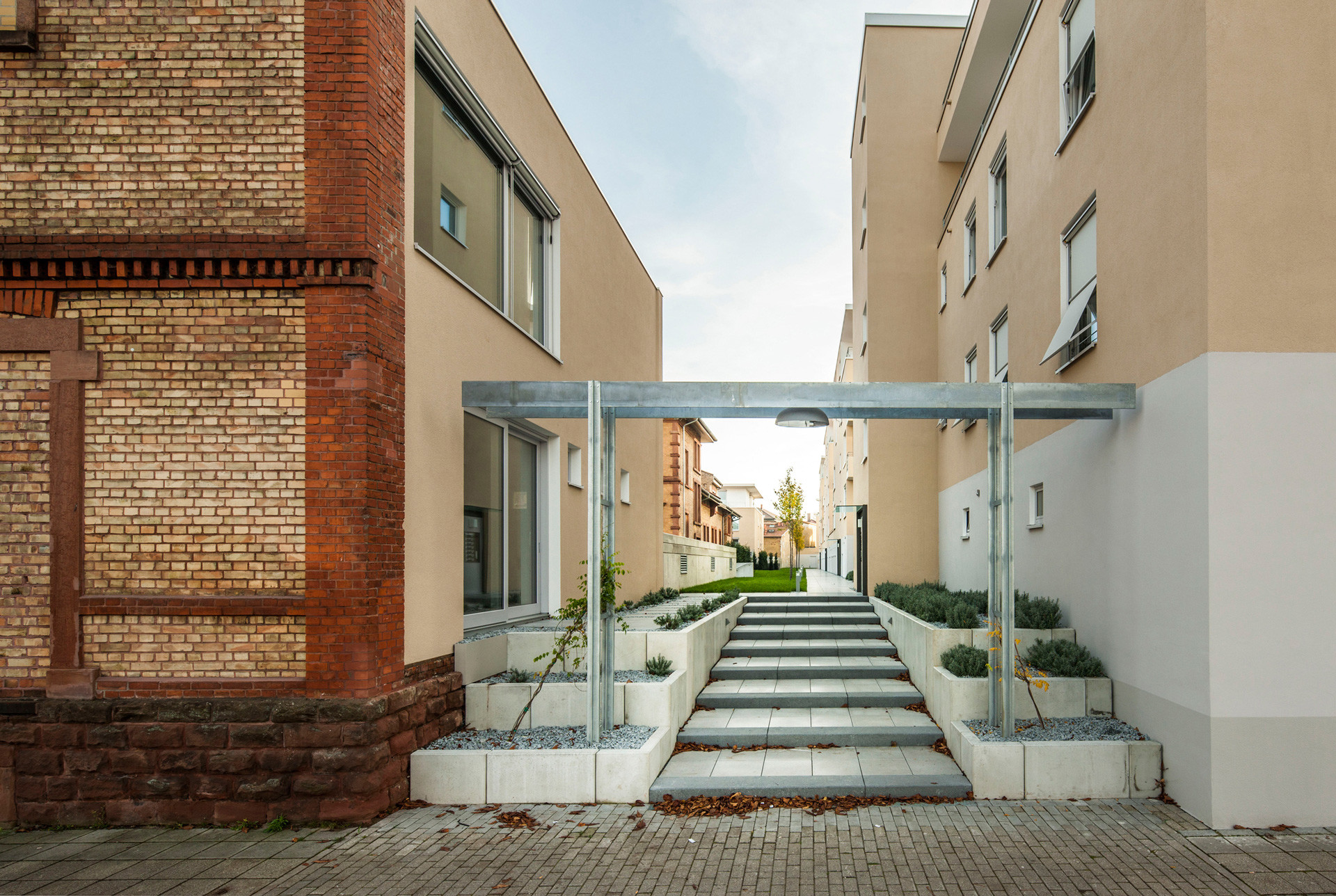 In zwei Reihen erstrecken sich die Gebäude auf rechteckigen und quadratischen Grundrissen, dazwischen bildet ein Fußweg eine begrünte Achse