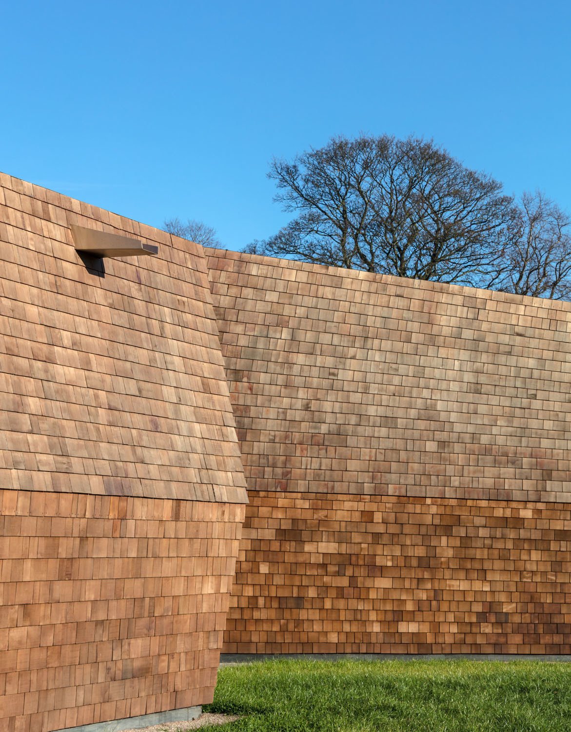 Die hervorstehenden, mit Holzschindeln bekleideten Volumen beherbergen Therapie- und Gruppenräume sowie den Besprechungsraum