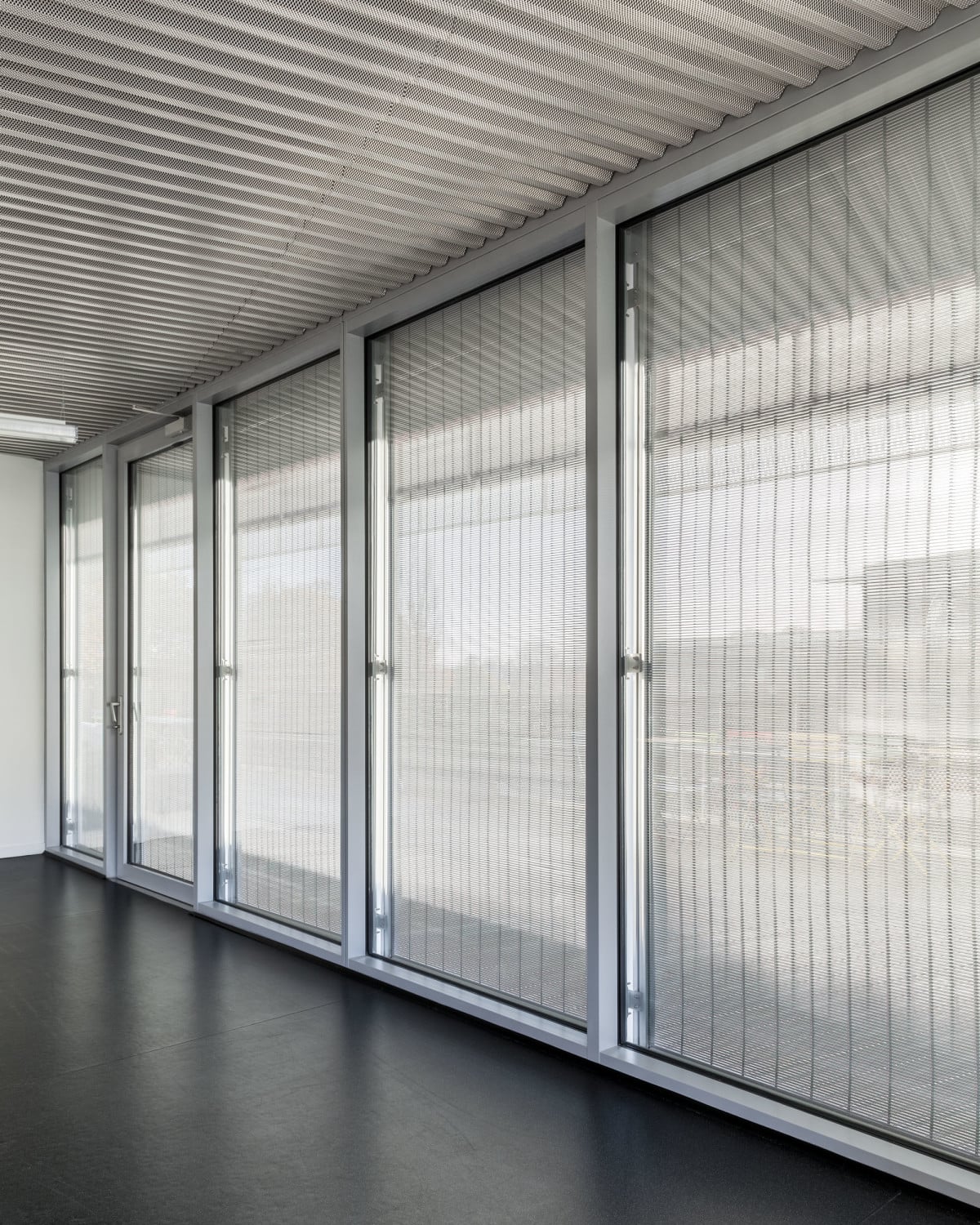 Einem Rollladen ähnlich, lassen sich die Aluminiumprofile wie feine Lamellen öffnen oder schließen und regulieren in den Innenräumen des Forschungsgebäudes auf dem Neurocampus Bordeaux den Lichteinfall.