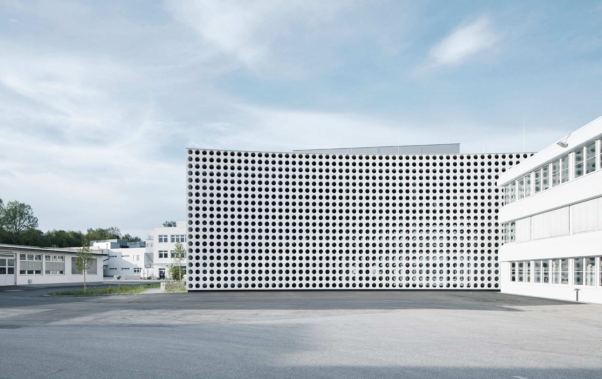 Wie ein Brise Soleil sitzt die Fassade aus Fertigteilplatten vor einer Stahl-Glas-Hülle