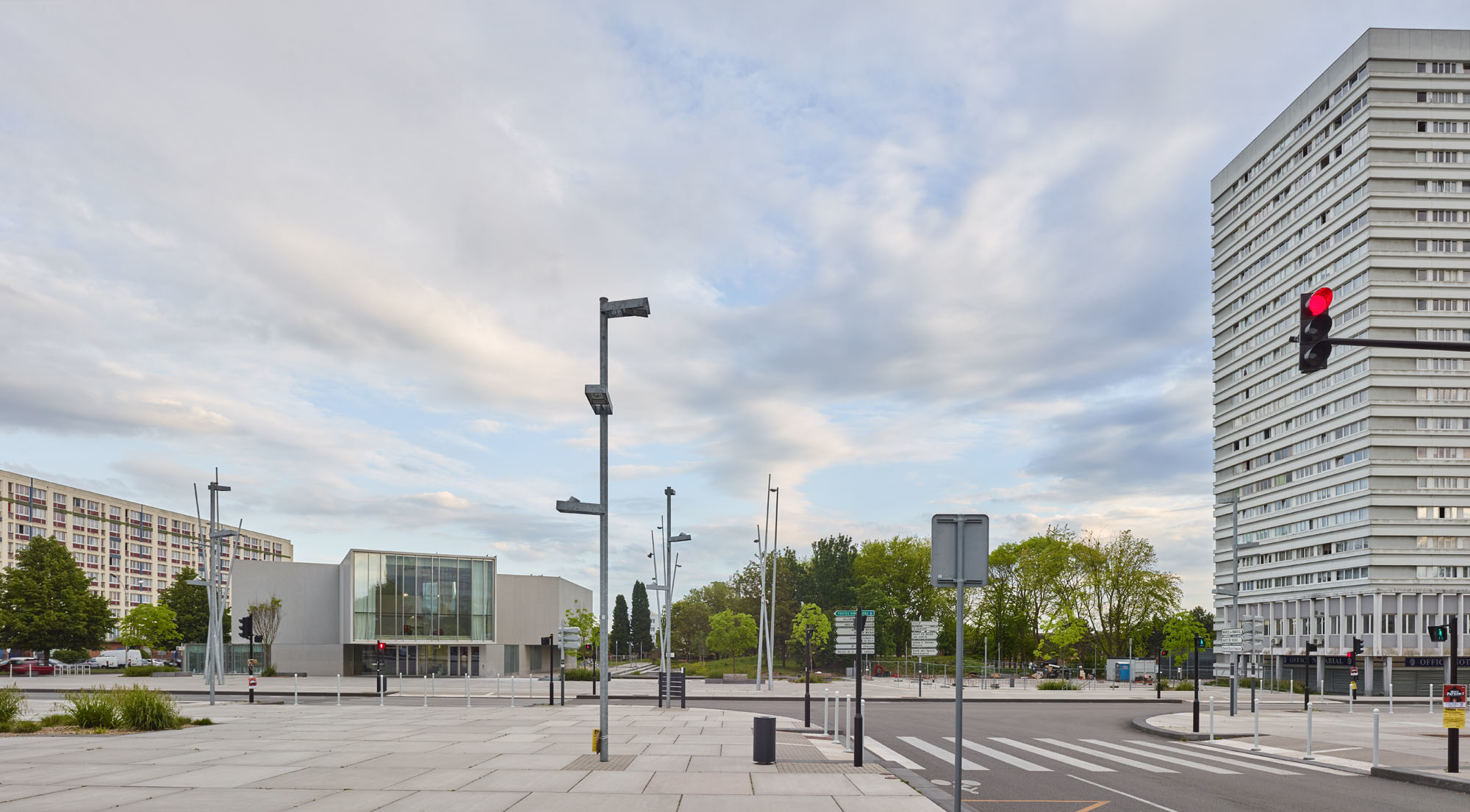 Der multifunktionale Neubau ruht auf dem Place de l'Europe, zu Füßen von betagten Wohnhochhäusern, und ist Teil eines Stadterneuerungsprojektes im Quartier Nouveau Mons