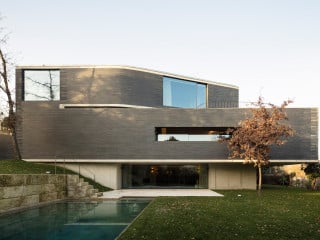 Nach Plänen von NØARQ entstand dieses Wohnhaus, das sich auf drei Ebenen in einen Hang schmiegt (Südseite)