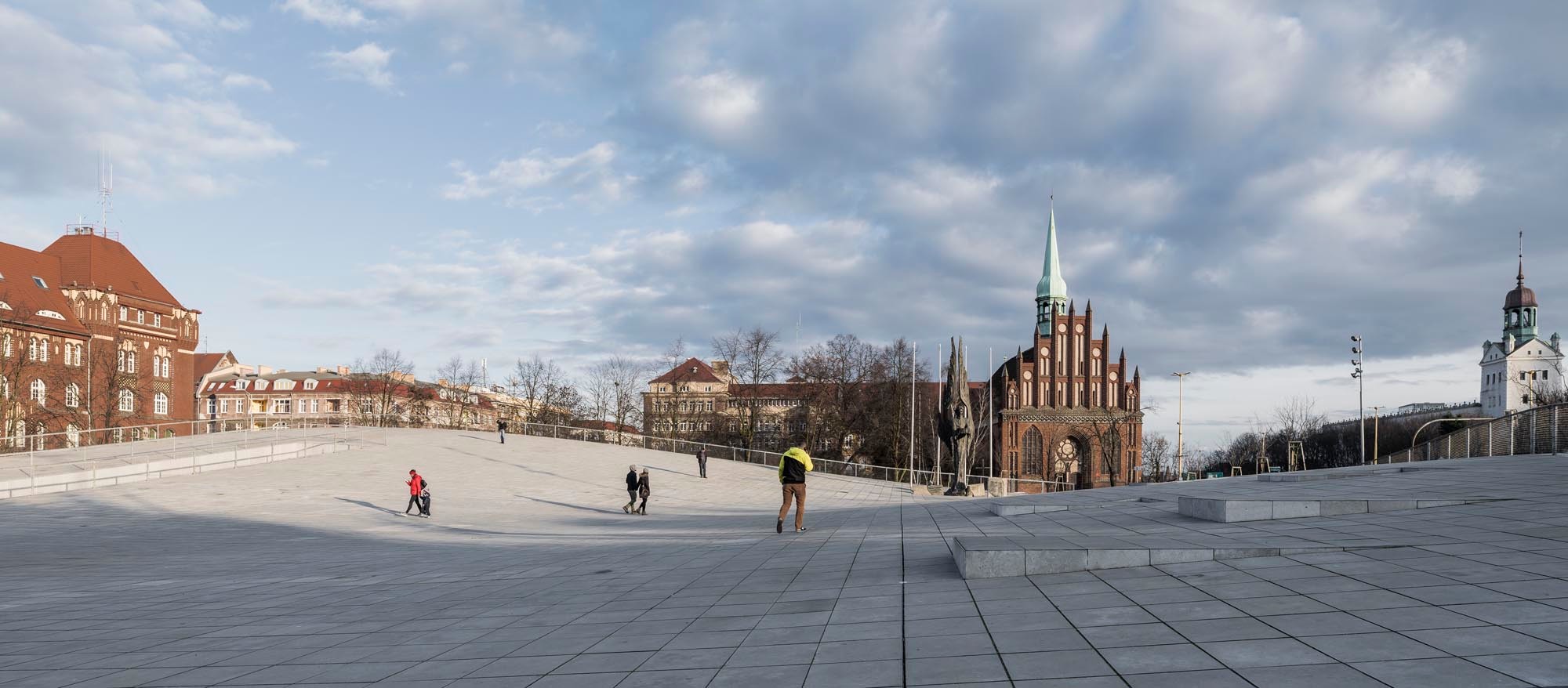 Die Architekten von KWK Promes aus Kattowitz entwarfen ein teilweise im Erdreich versenktes Bauwerk, dessen weites Dach als öffentlicher Platz begehbar ist