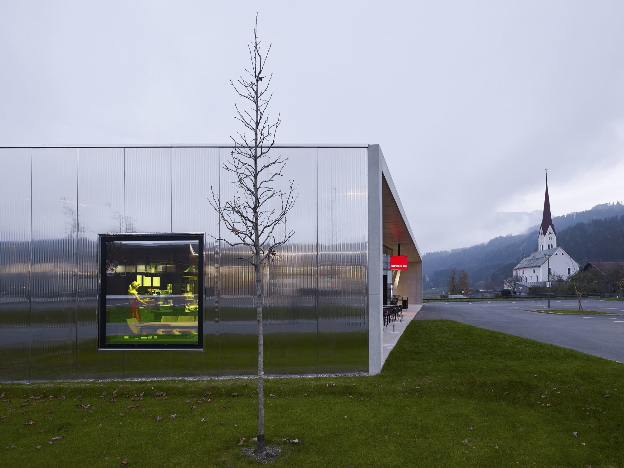 Die Ost-, West- und Nordseiten des Supermarkts sind mit polierten Edelstahlpaneelen verkleidet, welche die umliegende Landschaft unterschiedlich reflektieren