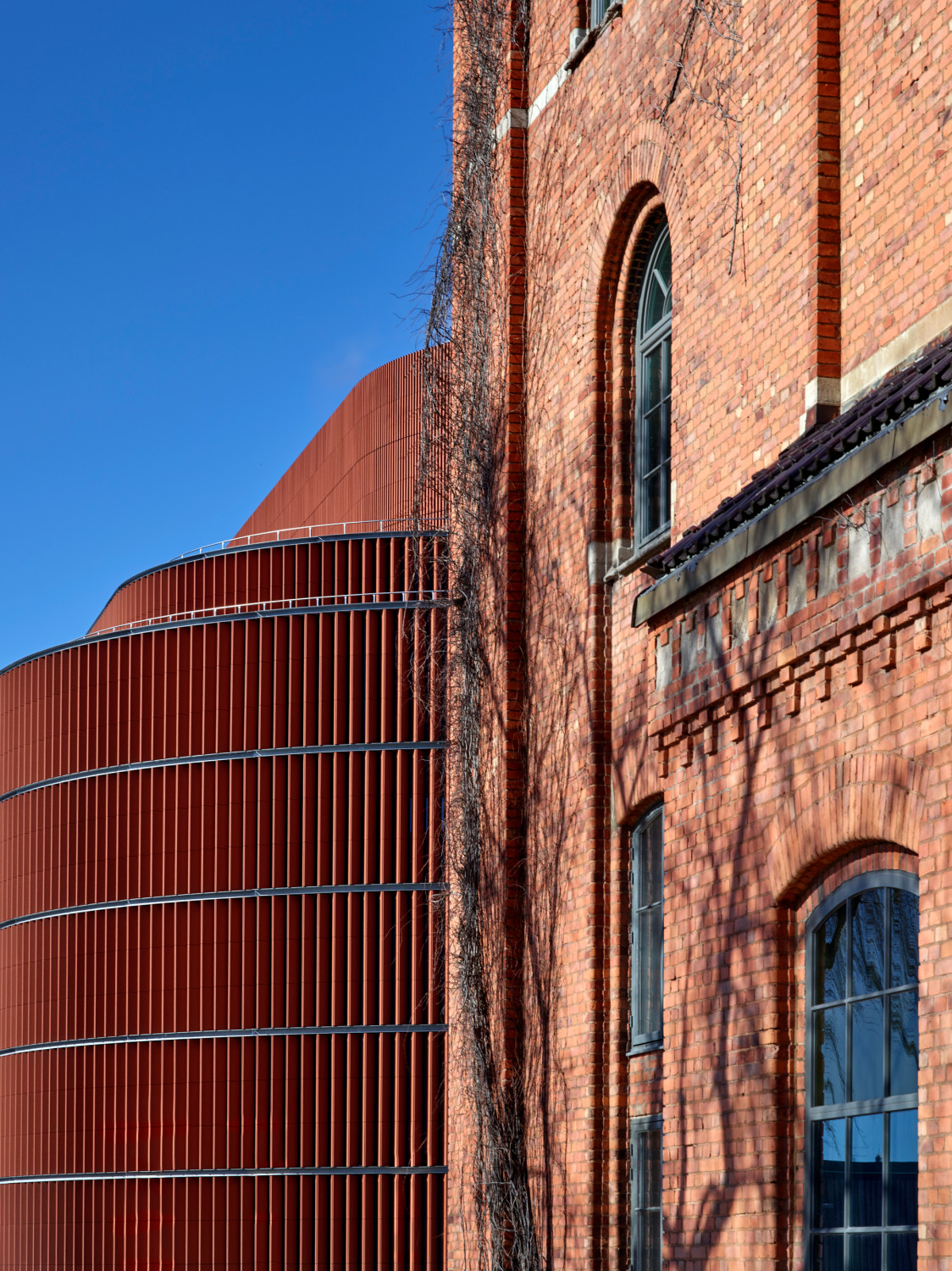 Die rote Keramikfassade tritt in Dialog mit den historischen Backsteinbauten vor Ort