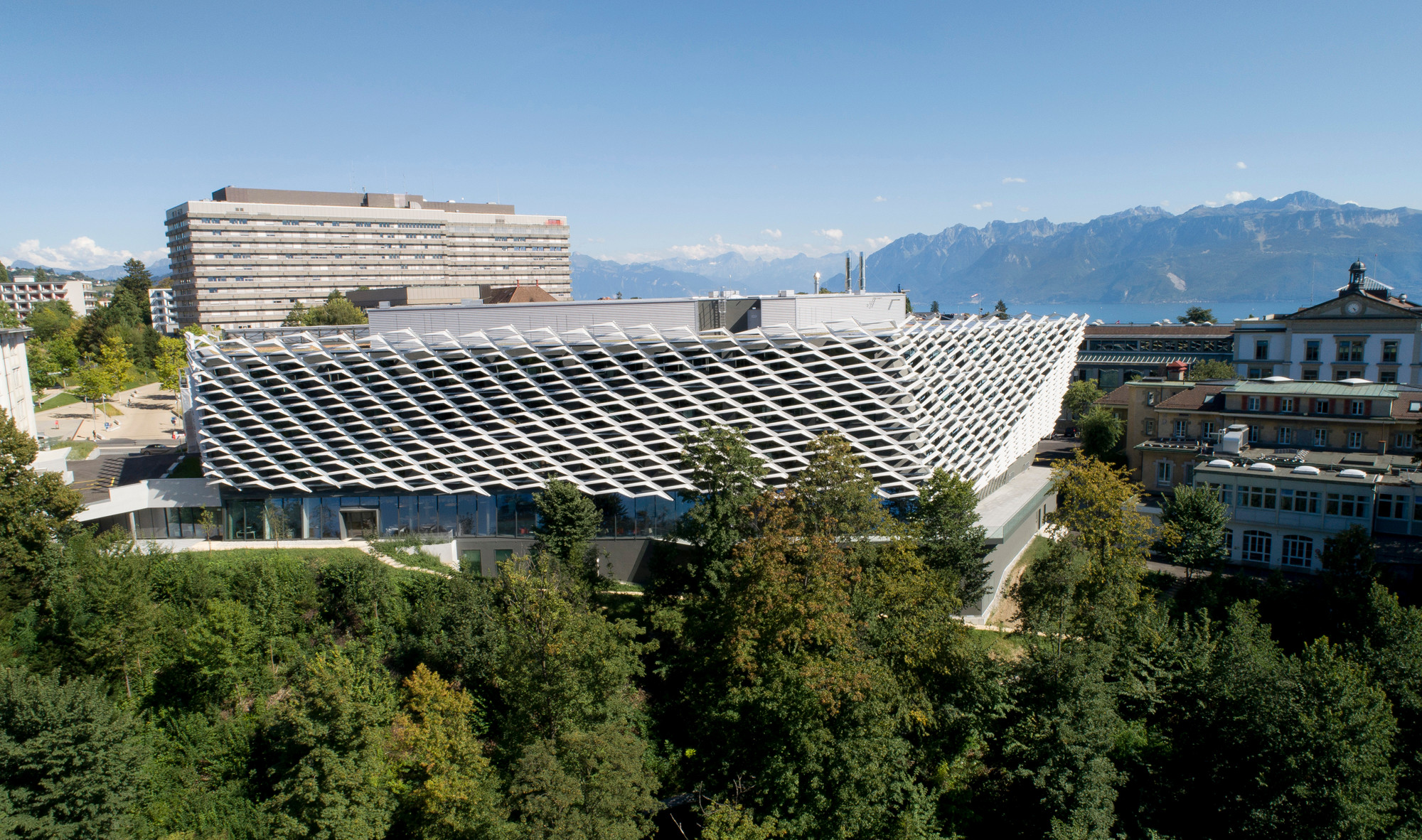 Am Rande eines Plateaus schließt der Neubau an ein bestehendes Gebäude der Universitätsklinik an.