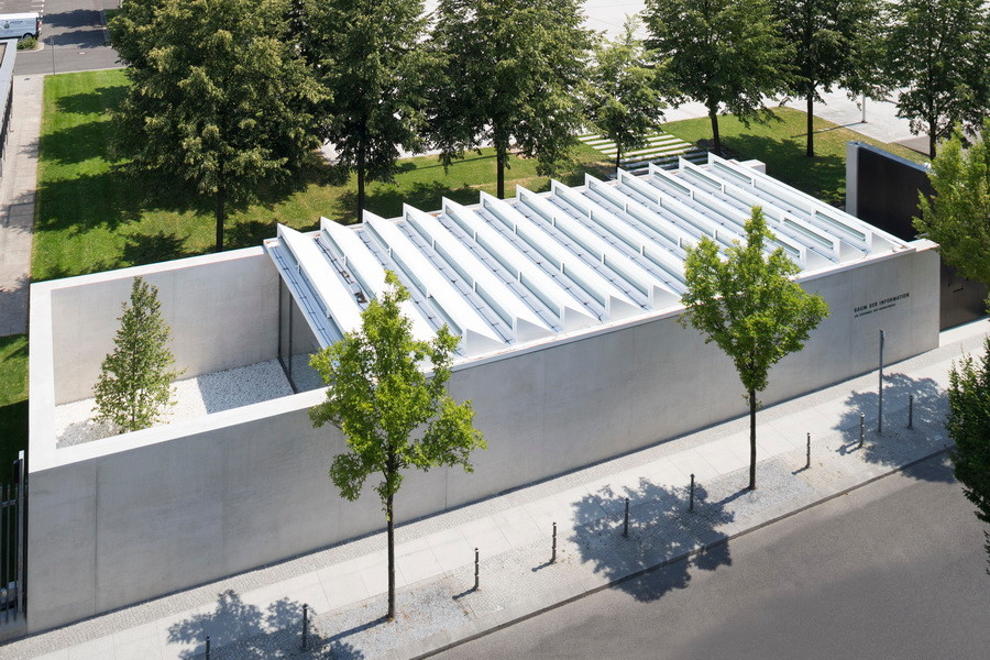 Drei geschlossene Wände aus glattem Sichtbeton umschließen U-förmig einen Hof und den Ausstellungsraum, der von einem Sheddach überdeckt ist.