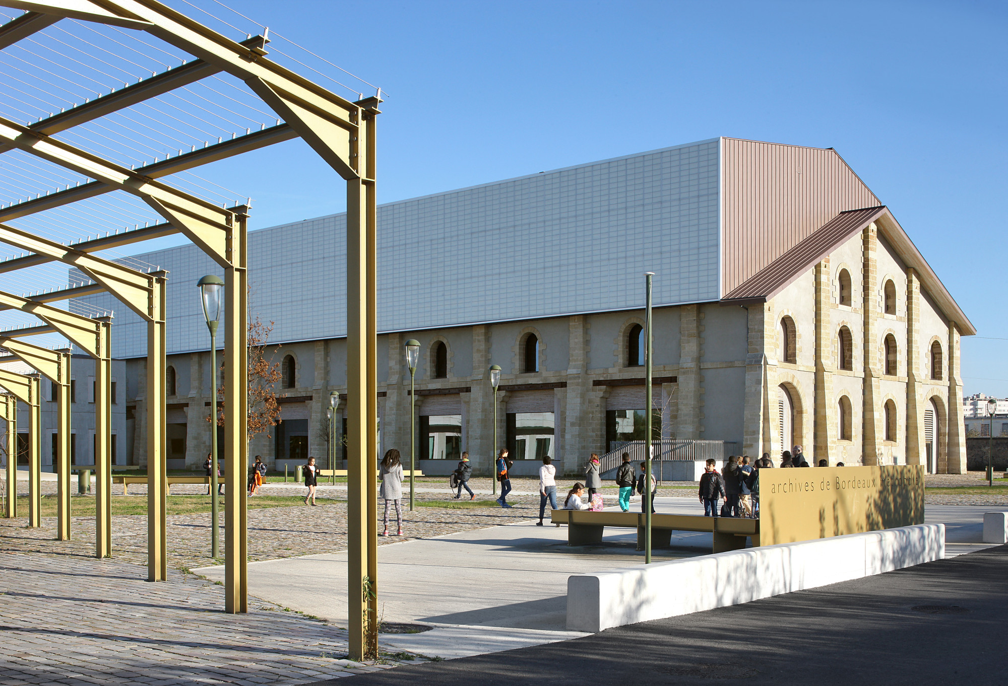 Nach einem Brand blieben nur die Fassaden des 78 m langen Bestandsgebäudes erhalten. Die neuen Archivräume ragen mit einer transluzenten Fassade und asymmetrischer Kubatur daraus empor.