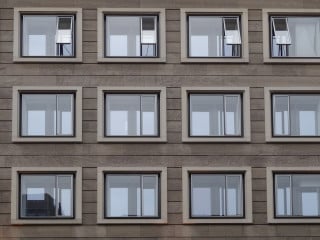 Typische Außenfassade mit Fenstern, Türen und Lüftungsöffnungen. Die beiden Lüftungsöffnungen im 1. OG wurden hier ungünstig zum Straßenverkehr und zu einer Haltestelle des öffentlichen Personennahverkehrs hin ausgerichtet. Bei unzureichender Schalldämmung der Lüftungsöffnungen können Brems- und Anfahrgeräusche der Busse sowie Gespräche wartender Fahrgäste in Wohnräume übertragen werden.