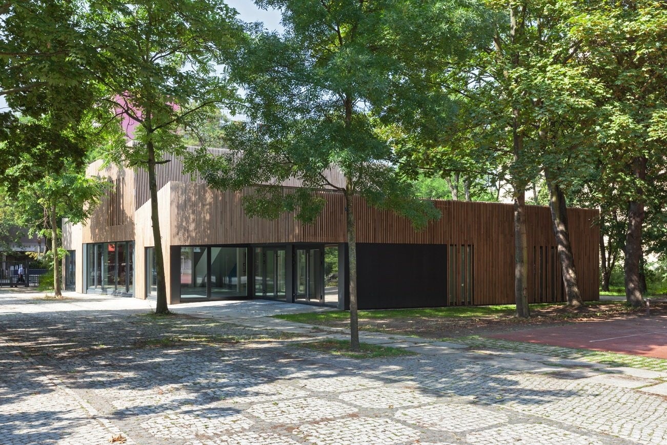 Der Neubau fügt sich mit seinem lebendigen Erscheinungsbild aus unterschiedlich hohen Pultdächern und leicht geknickten Fassaden in die begrünte Umgebung ein.