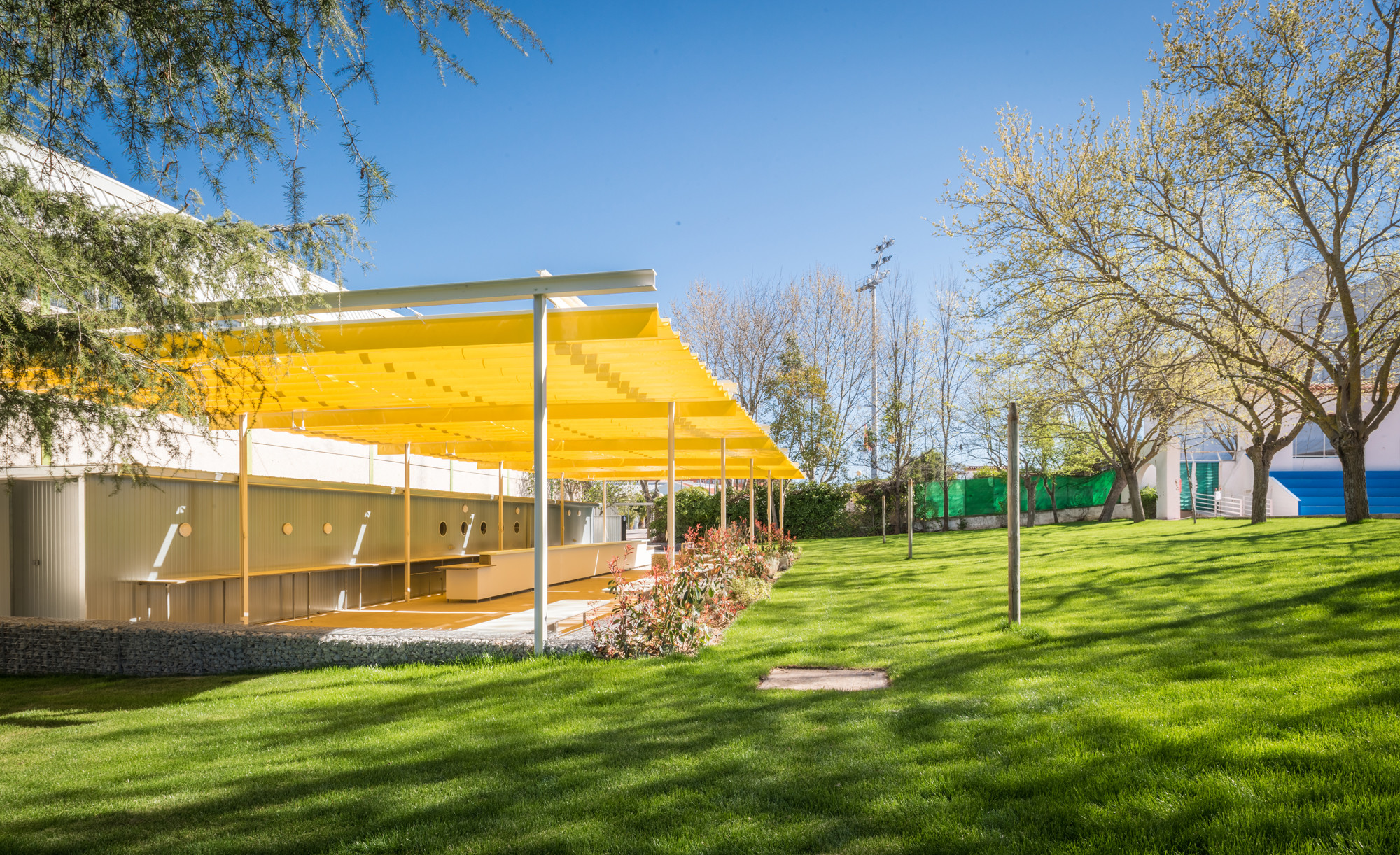 Die Terrasse wird von einer Pergola mit gelbem Sonnendach überspannt.