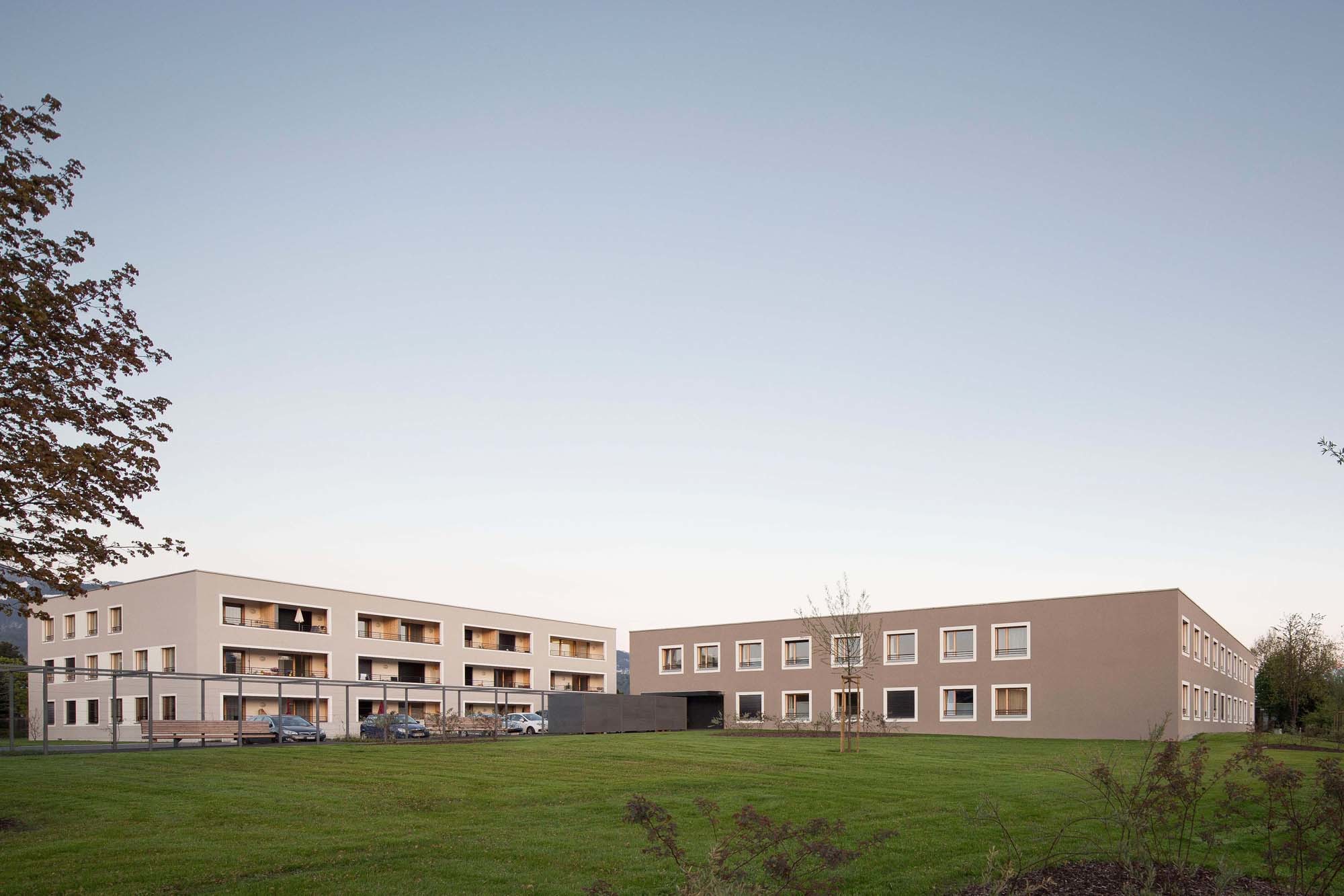 Während das von der Straße zurückgesetzte, zweigeschossige Pflegeheim in einem warmen Braunton verputzt ist, zeigt das dreigeschossige Wohnhaus ein helles Taupe.