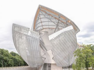 In dem weitläufigen Pariser Stadtpark Bois du Boulogne erhebt sich der geschwungene, von transluzenten Glassegeln umhüllte Baukörper der Stiftung Louis Vuitton.