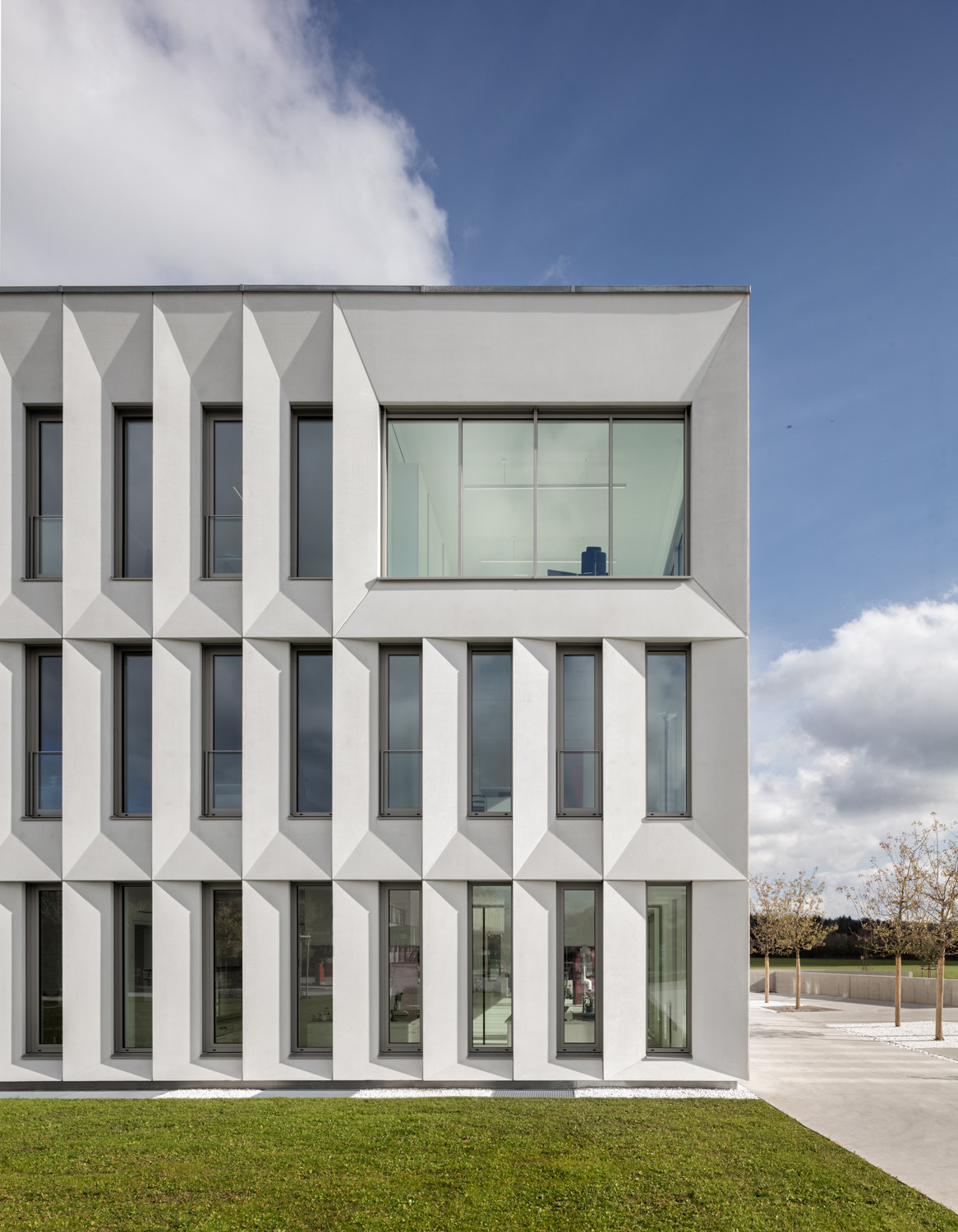Die Fassade besteht aus einer dreidimensional geformten Gebäudehülle aus glattem Beton.