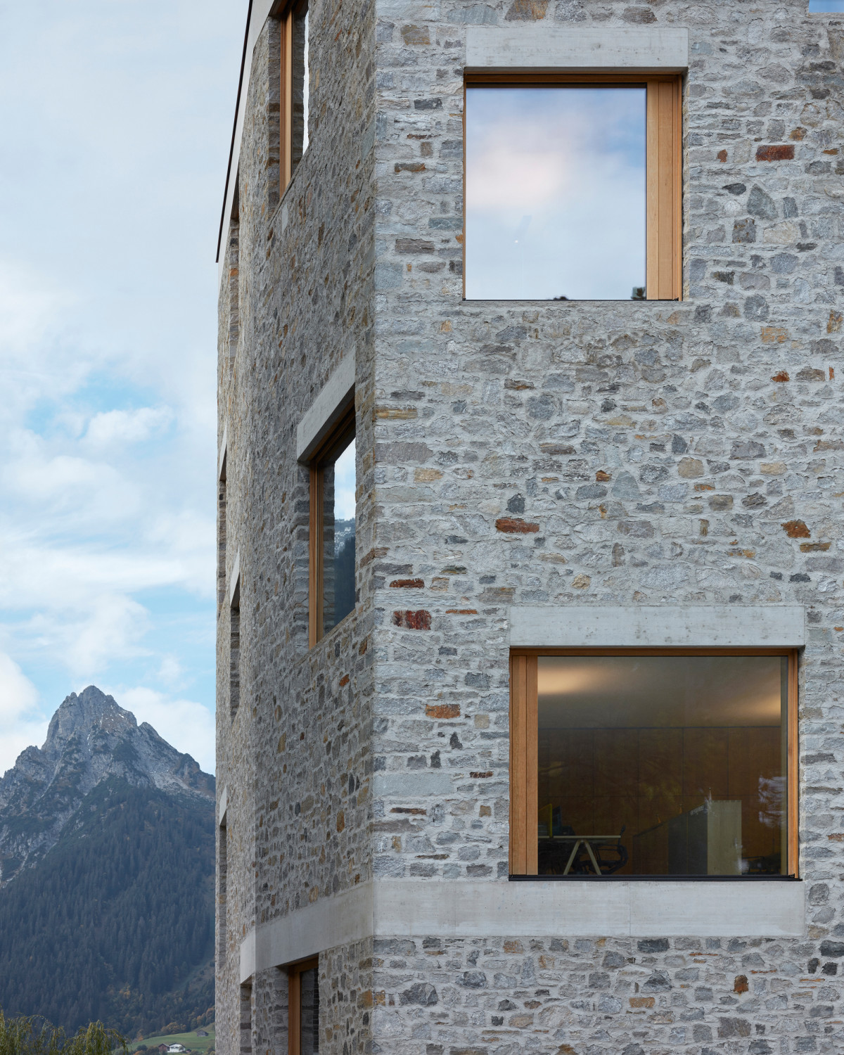 Lochfenster mit unterschiedlichen Maßen und Positionen lockern die monolithische Wirkung des Baus auf.